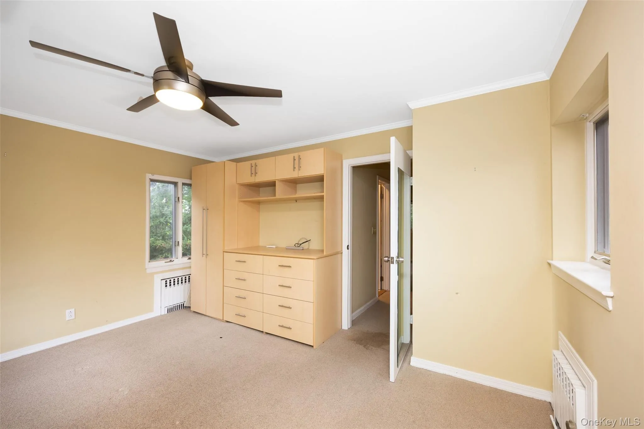 Bedroom featuring crown molding, light carpet, radiator heating unit, and ceiling fan Bedroom featuring crown molding, light carpet, radiator heating unit, and ceiling fan