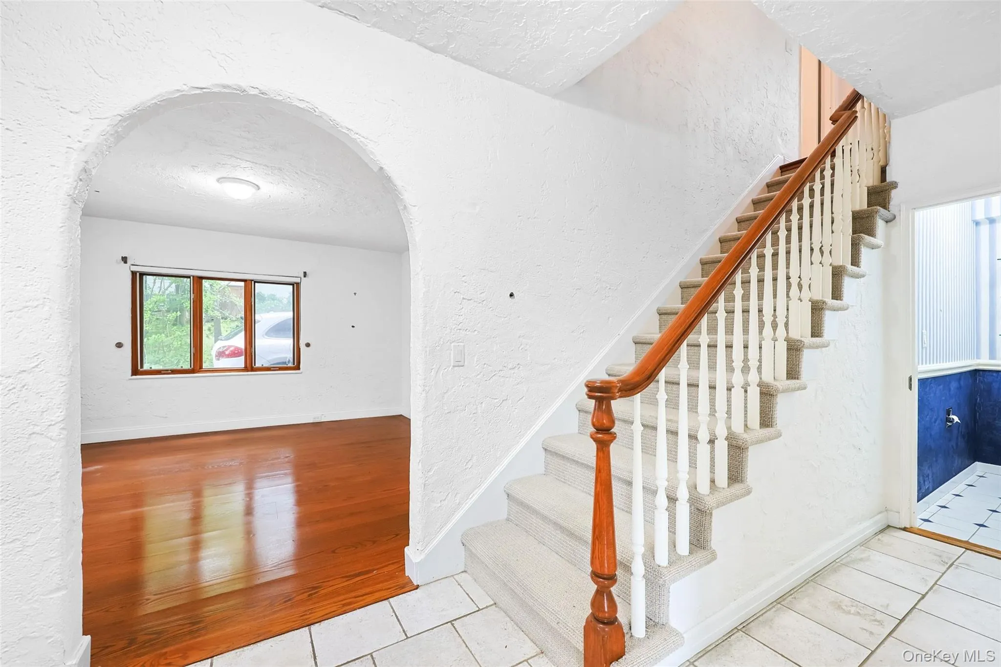 Stairway with a textured wall, arched walkways, a textured ceiling, and tile patterned floors Stairway with a textured wall, arched walkways, a textured ceiling, and tile patterned floors