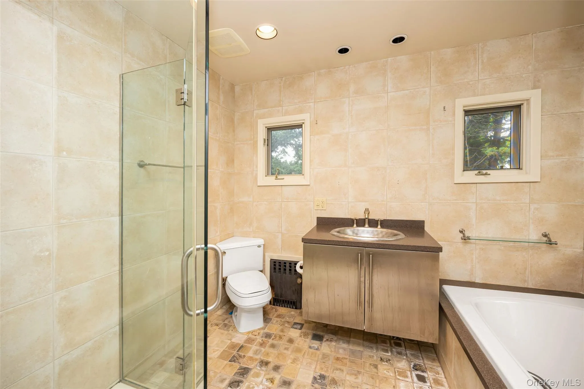 Full bath with recessed lighting, a shower stall, radiator, tile walls, and a garden tub Full bath with recessed lighting, a shower stall, radiator, tile walls, and a garden tub