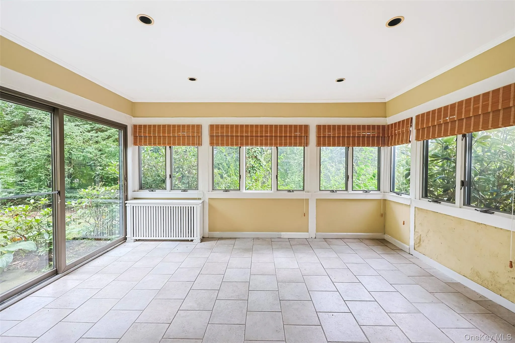 Unfurnished sunroom with ornamental molding, radiator heating unit, tile patterned flooring, and recessed lighting Unfurnished sunroom with ornamental molding, radiator heating unit, tile patterned flooring, and recessed lighting