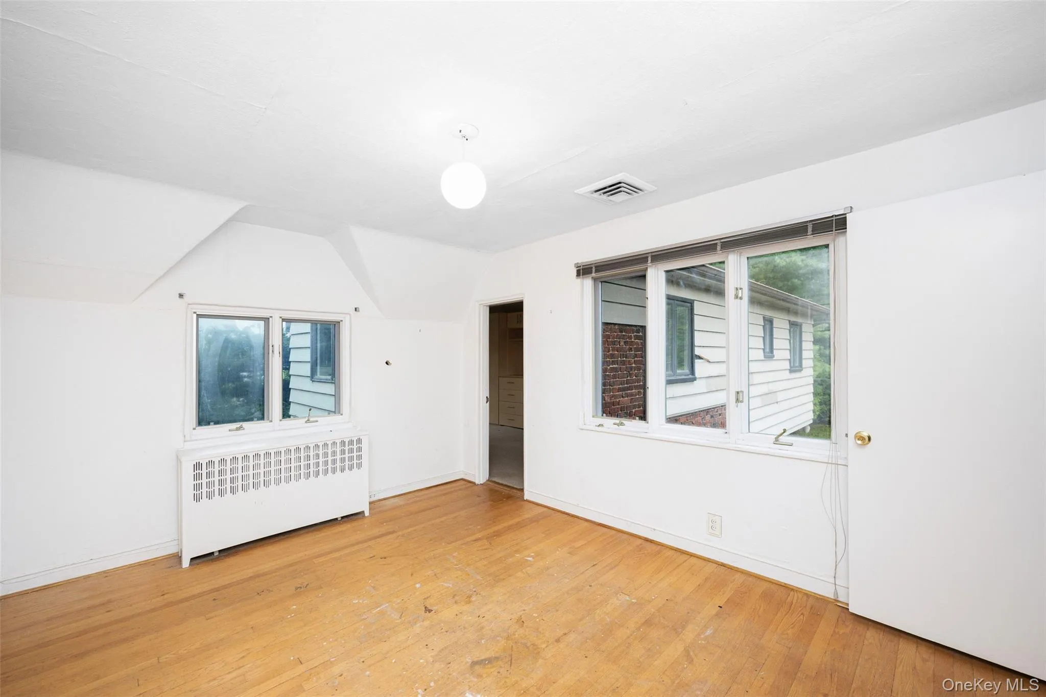 Additional living space featuring radiator, healthy amount of natural light, and wood-type flooring Additional living space featuring radiator, healthy amount of natural light, and wood-type flooring