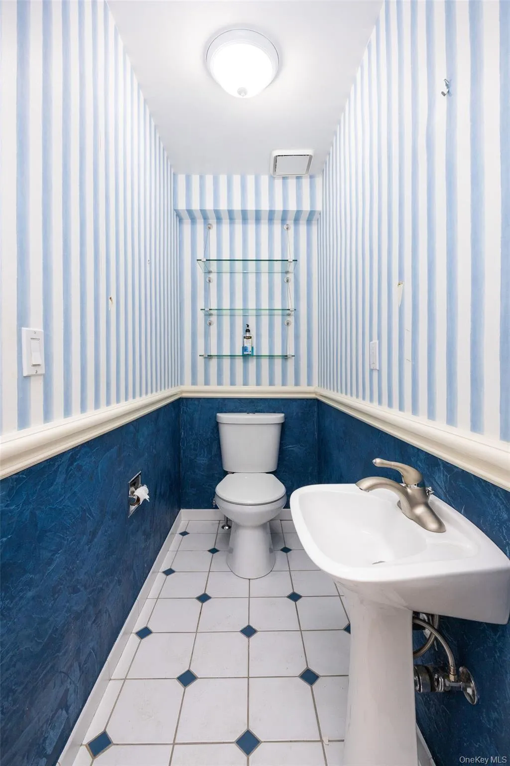 Bathroom featuring a wainscoted wall, wallpapered walls, and tile patterned floors Bathroom featuring a wainscoted wall, wallpapered walls, and tile patterned floors