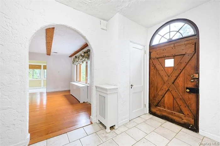 Entryway featuring arched walkways, a textured wall, plenty of natural light, a textured ceiling, and light tile patterned floors Entryway featuring arched walkways, a textured wall, plenty of natural light, a textured ceiling, and light tile patterned floors