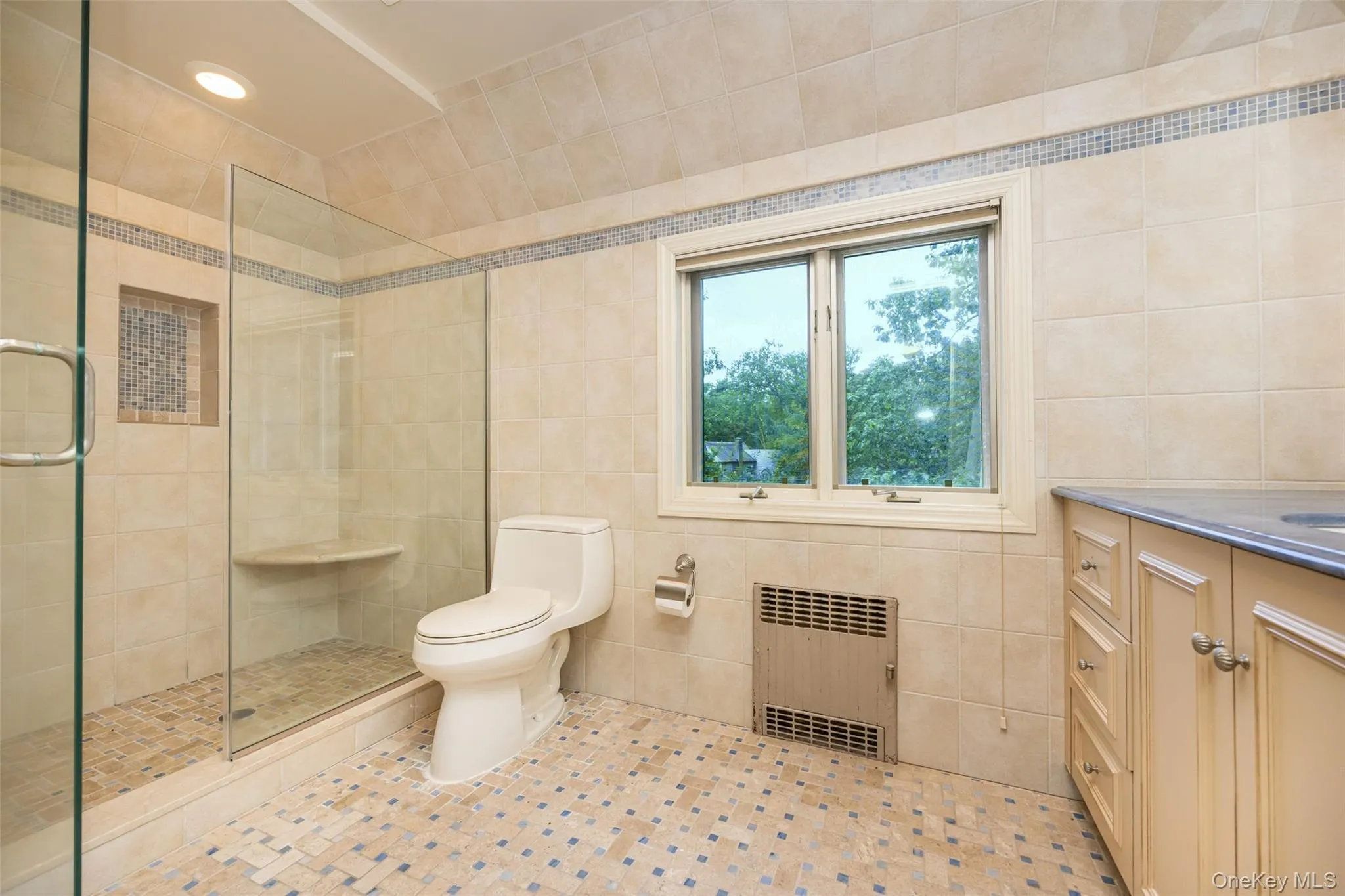 Bathroom with tile walls, radiator, tiled shower, vanity, and tile patterned flooring Bathroom with tile walls, radiator, tiled shower, vanity, and tile patterned flooring