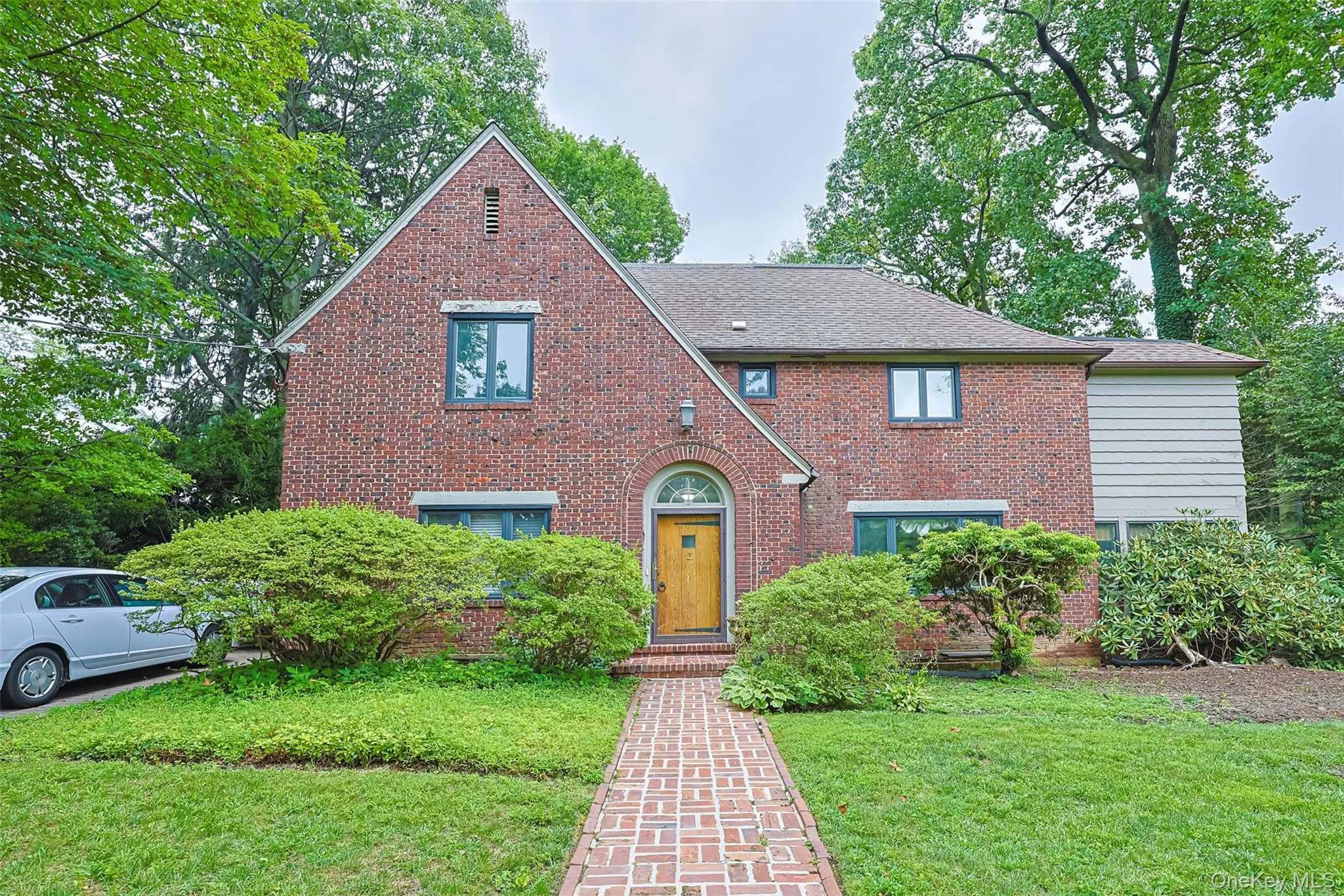 Tudor home with brick siding, a front lawn, and a shingled roof Tudor home with brick siding, a front lawn, and a shingled roof