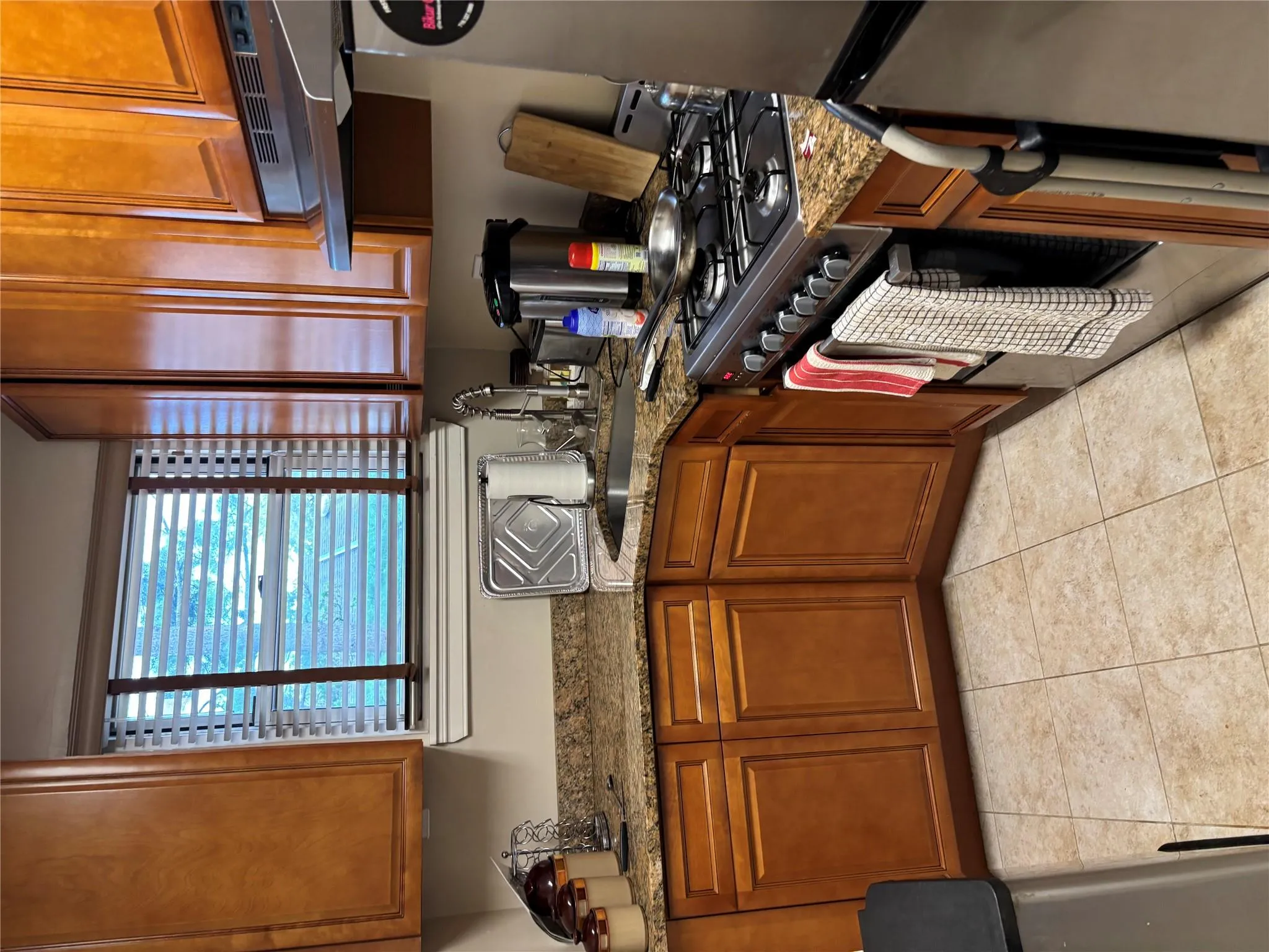 Kitchen featuring extractor fan, range, fridge, and brown cabinetry Kitchen featuring extractor fan, range, fridge, and brown cabinetry