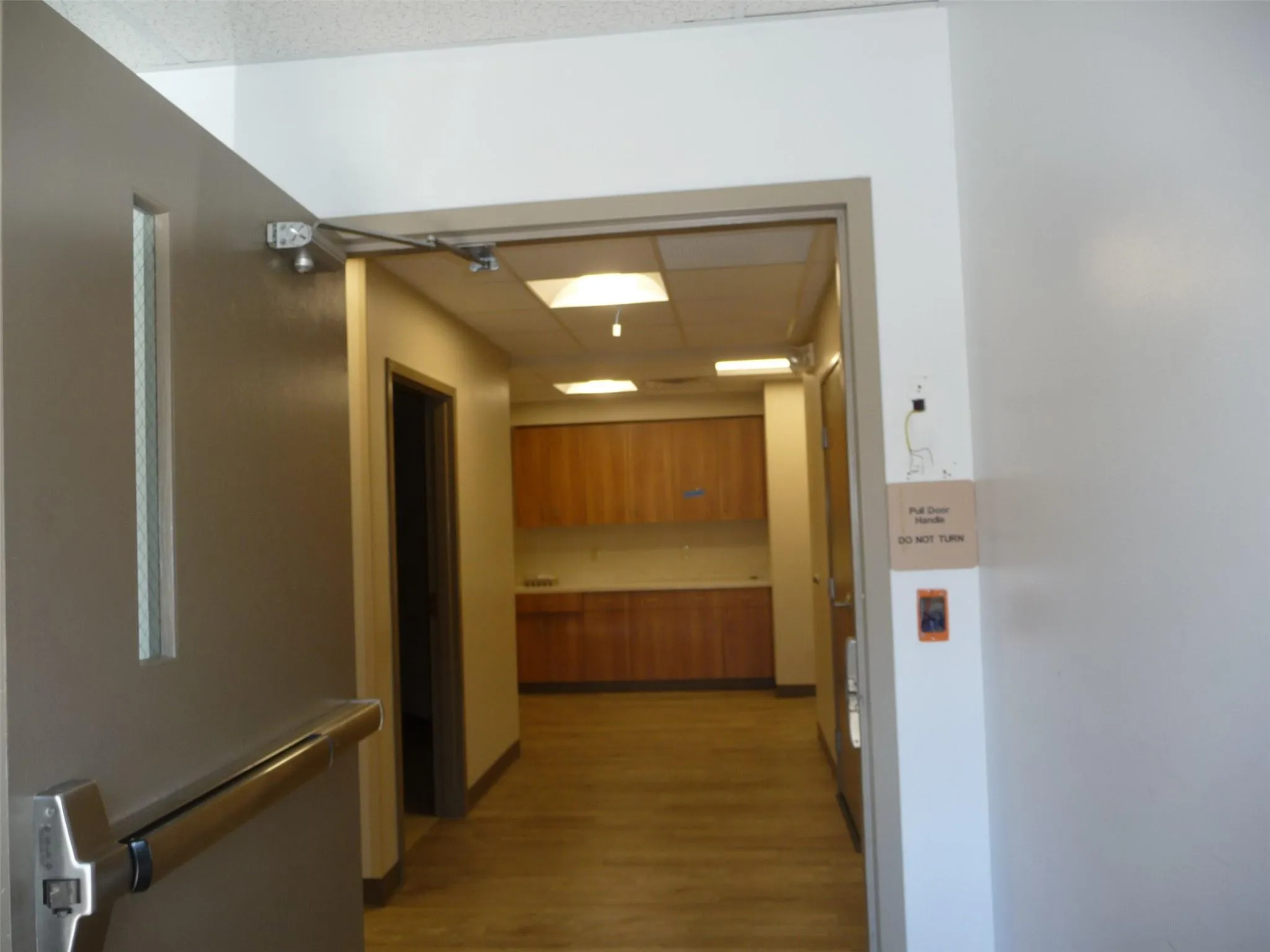 Corridor featuring light wood-style floors and a drop ceiling Corridor featuring light wood-style floors and a drop ceiling