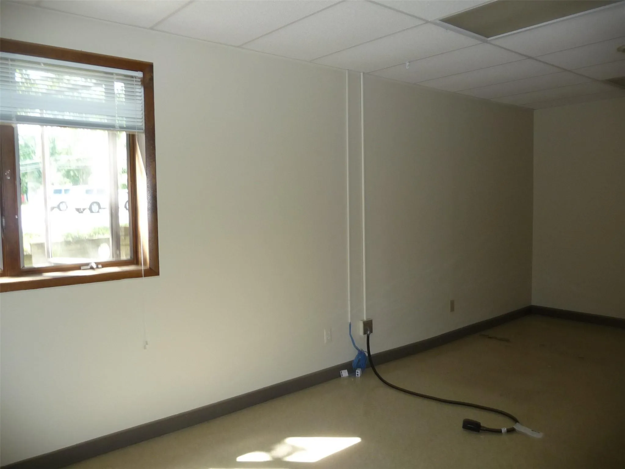 Empty room with a drop ceiling and baseboards Empty room with a drop ceiling and baseboards
