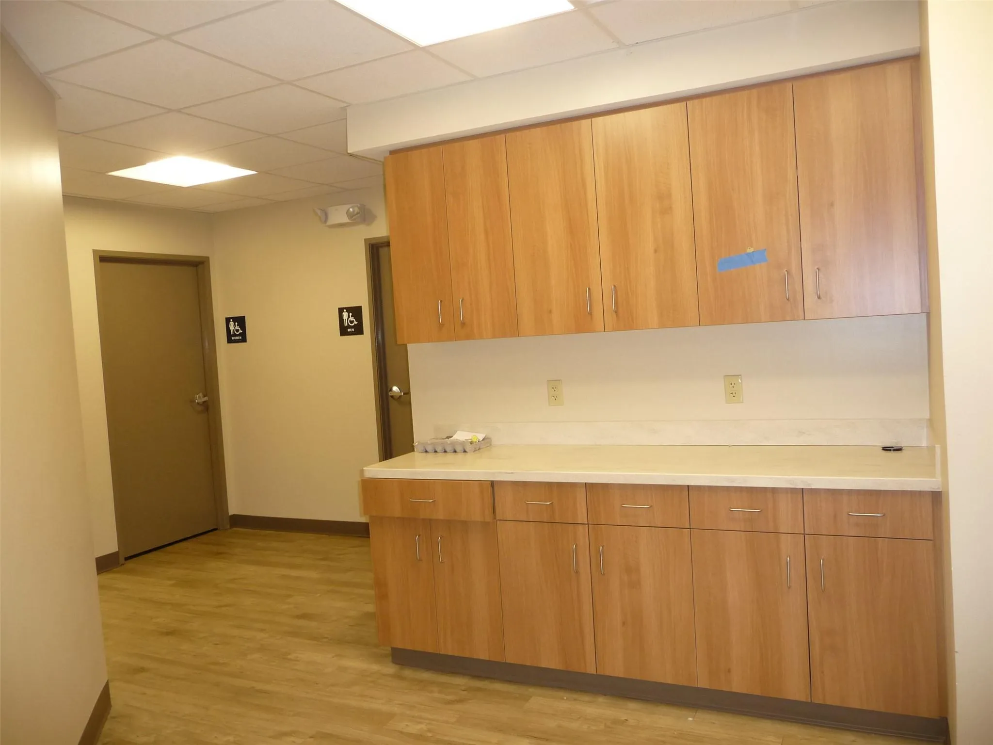 Kitchen featuring a paneled ceiling, light countertops, light wood-style floors, brown cabinets, and modern cabinets Kitchen featuring a paneled ceiling, light countertops, light wood-style floors, brown cabinets, and modern cabinets
