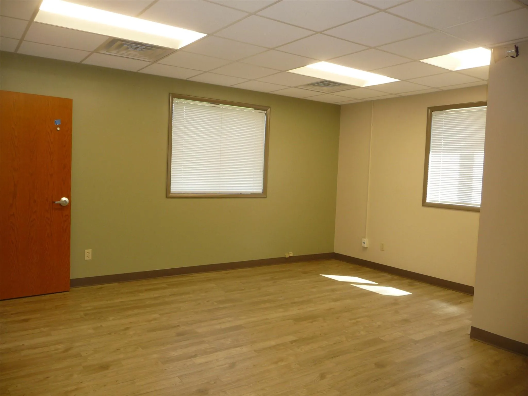 Spare room featuring light wood finished floors and a drop ceiling Spare room featuring light wood finished floors and a drop ceiling