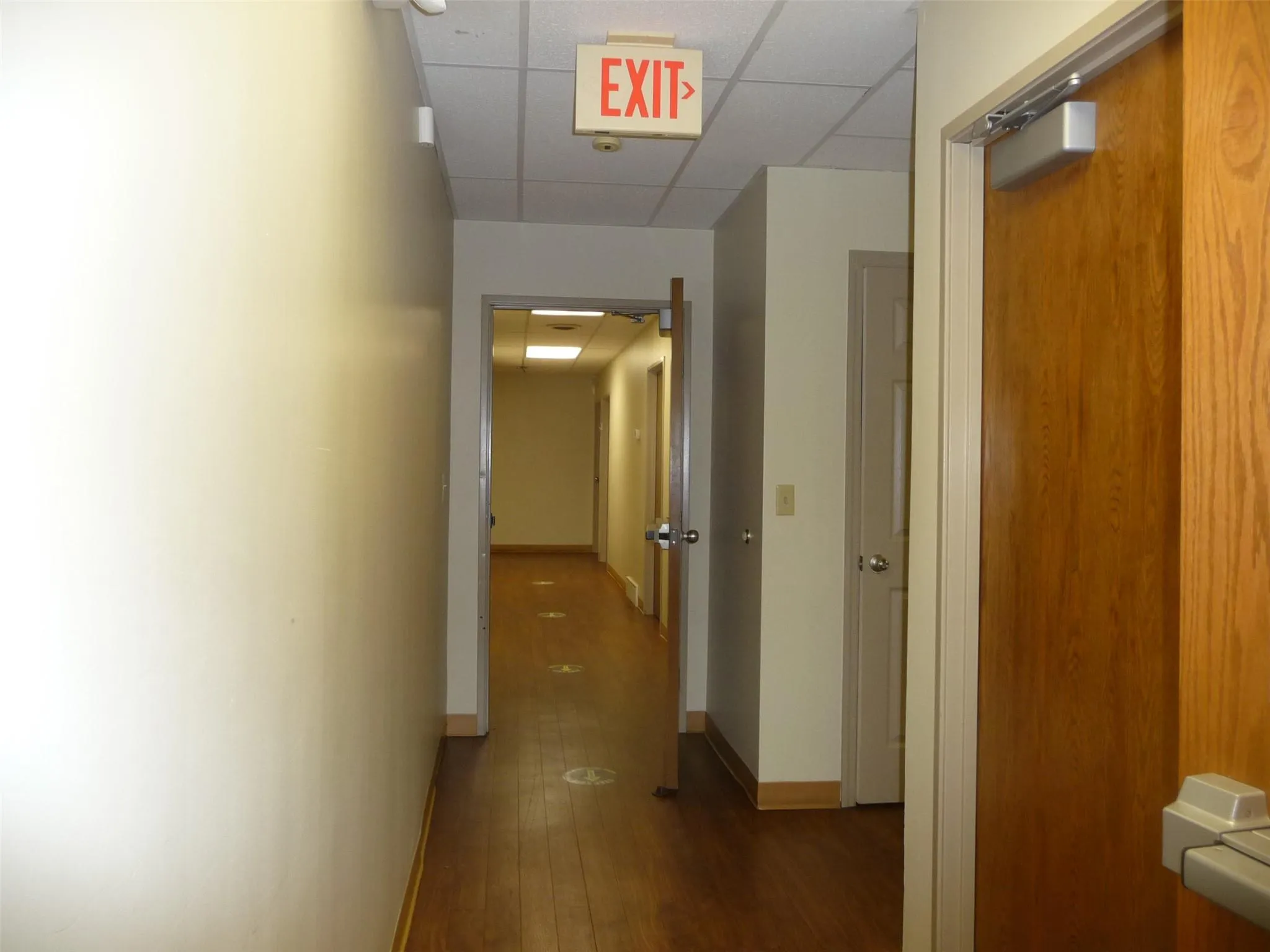 Hallway with a drop ceiling and hardwood / wood-style floors Hallway with a drop ceiling and hardwood / wood-style floors