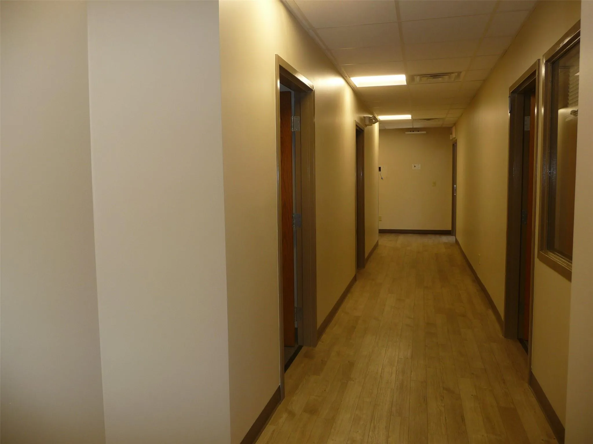 Hall with a paneled ceiling and light wood finished floors Hall with a paneled ceiling and light wood finished floors