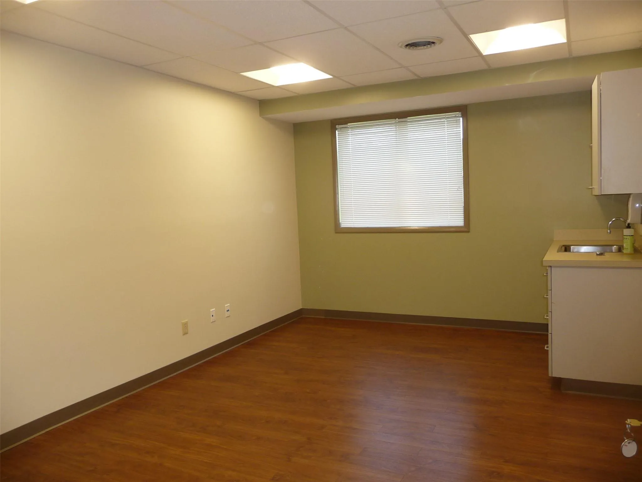 Unfurnished room with dark wood-style flooring and a drop ceiling Unfurnished room with dark wood-style flooring and a drop ceiling