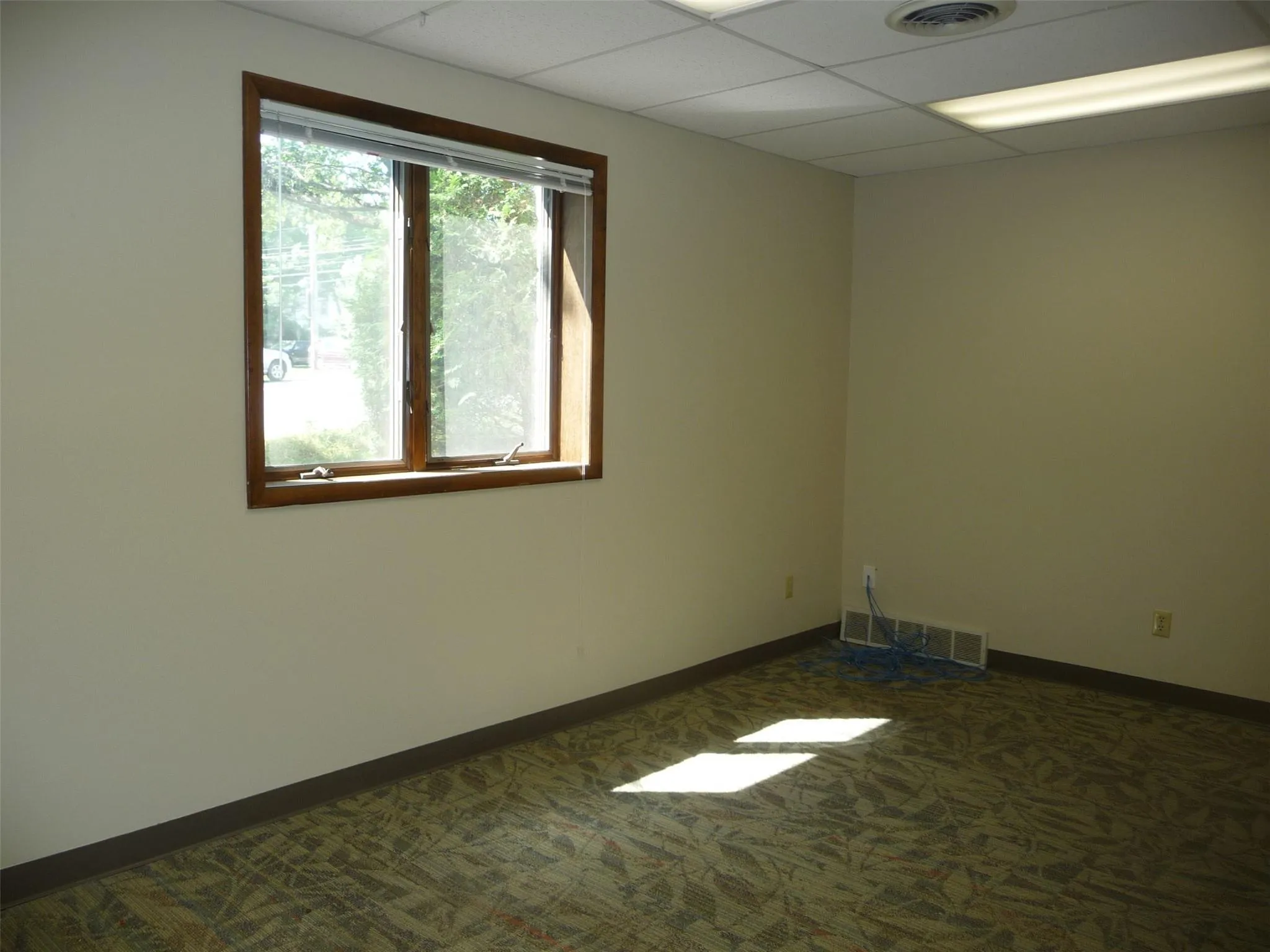 Spare room featuring dark carpet and a paneled ceiling Spare room featuring dark carpet and a paneled ceiling
