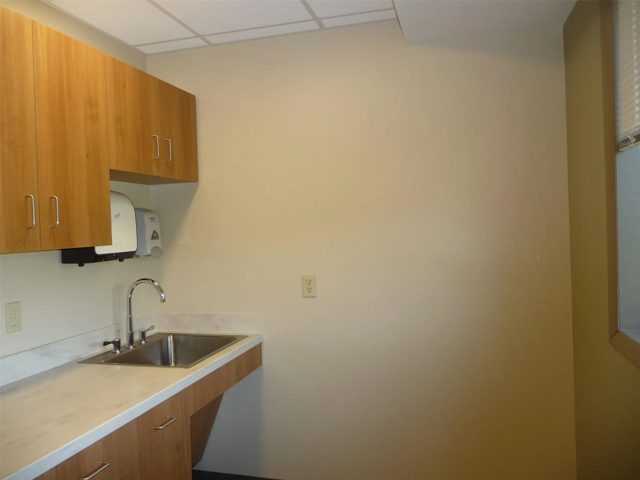 Kitchen with brown cabinets, light countertops, a drop ceiling, and modern cabinets Kitchen with brown cabinets, light countertops, a drop ceiling, and modern cabinets