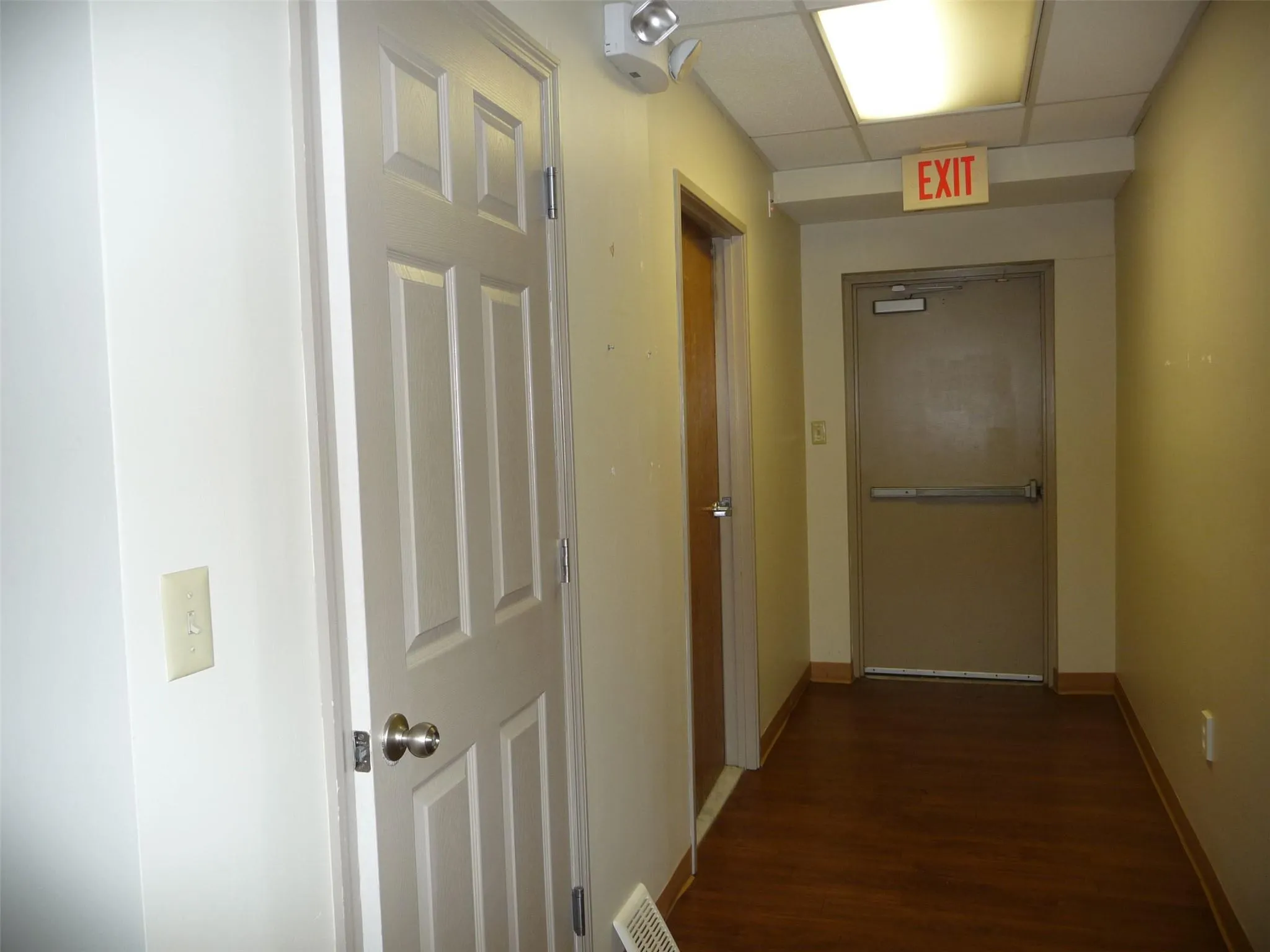 Hall featuring dark wood finished floors and a drop ceiling Hall featuring dark wood finished floors and a drop ceiling