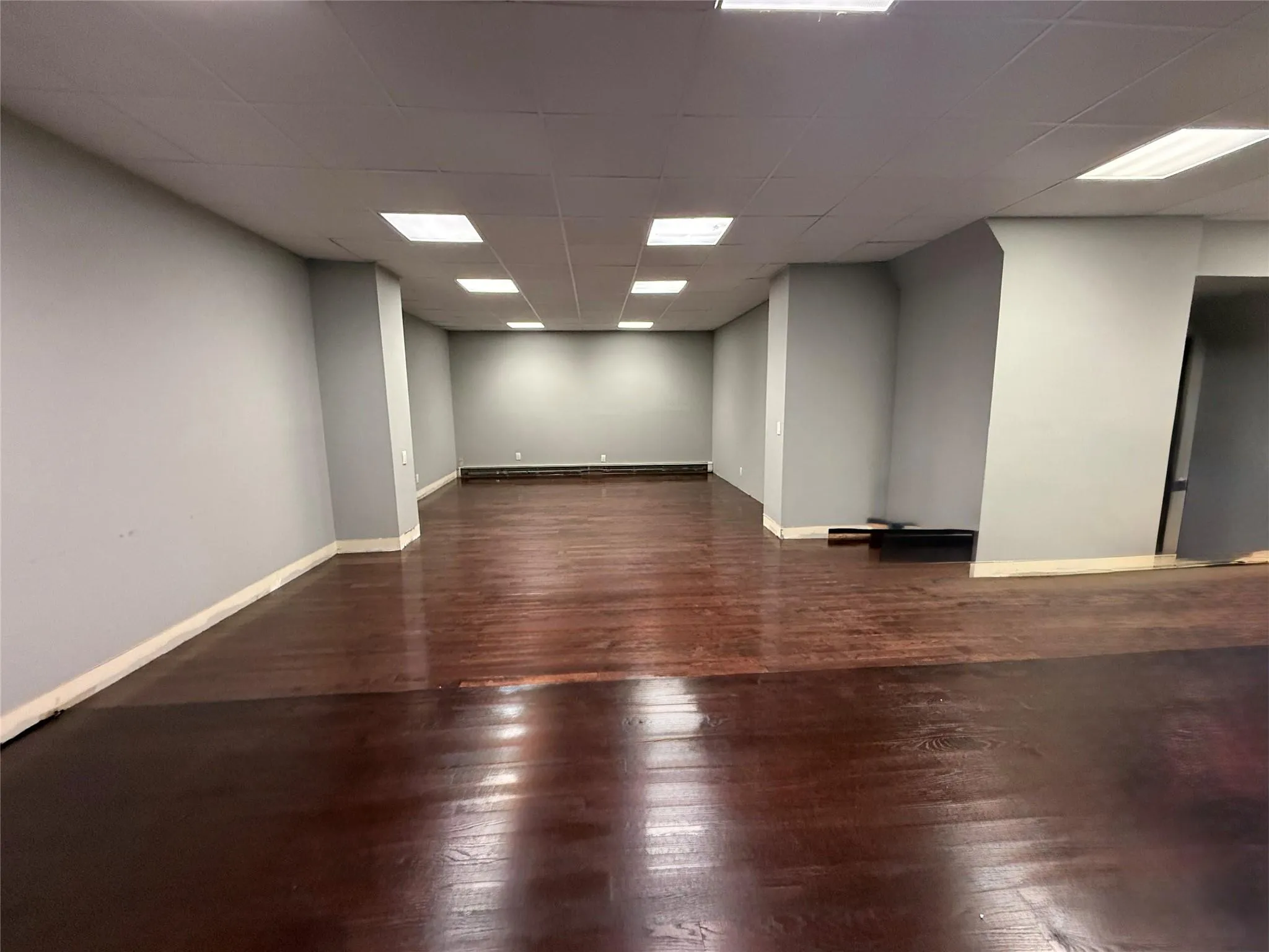 Unfurnished room with wood-type flooring and a paneled ceiling Unfurnished room with wood-type flooring and a paneled ceiling