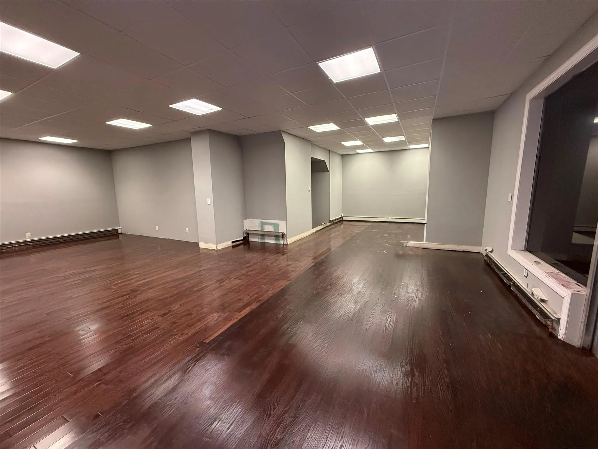 Spare room featuring a paneled ceiling, wood finished floors, and baseboard heating Spare room featuring a paneled ceiling, wood finished floors, and baseboard heating