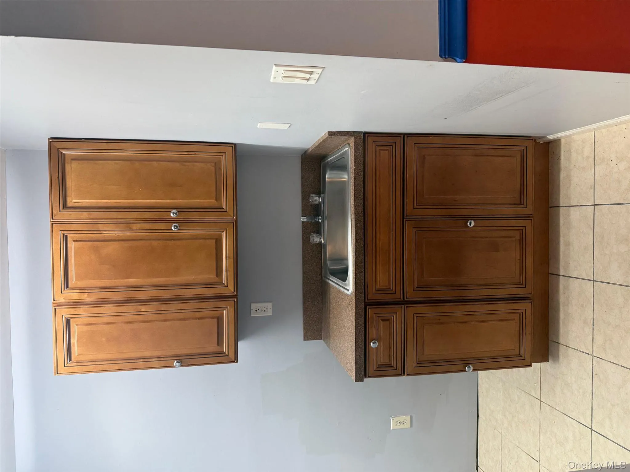 Kitchen featuring dark countertops, light tile patterned floors, and brown cabinets Kitchen featuring dark countertops, light tile patterned floors, and brown cabinets