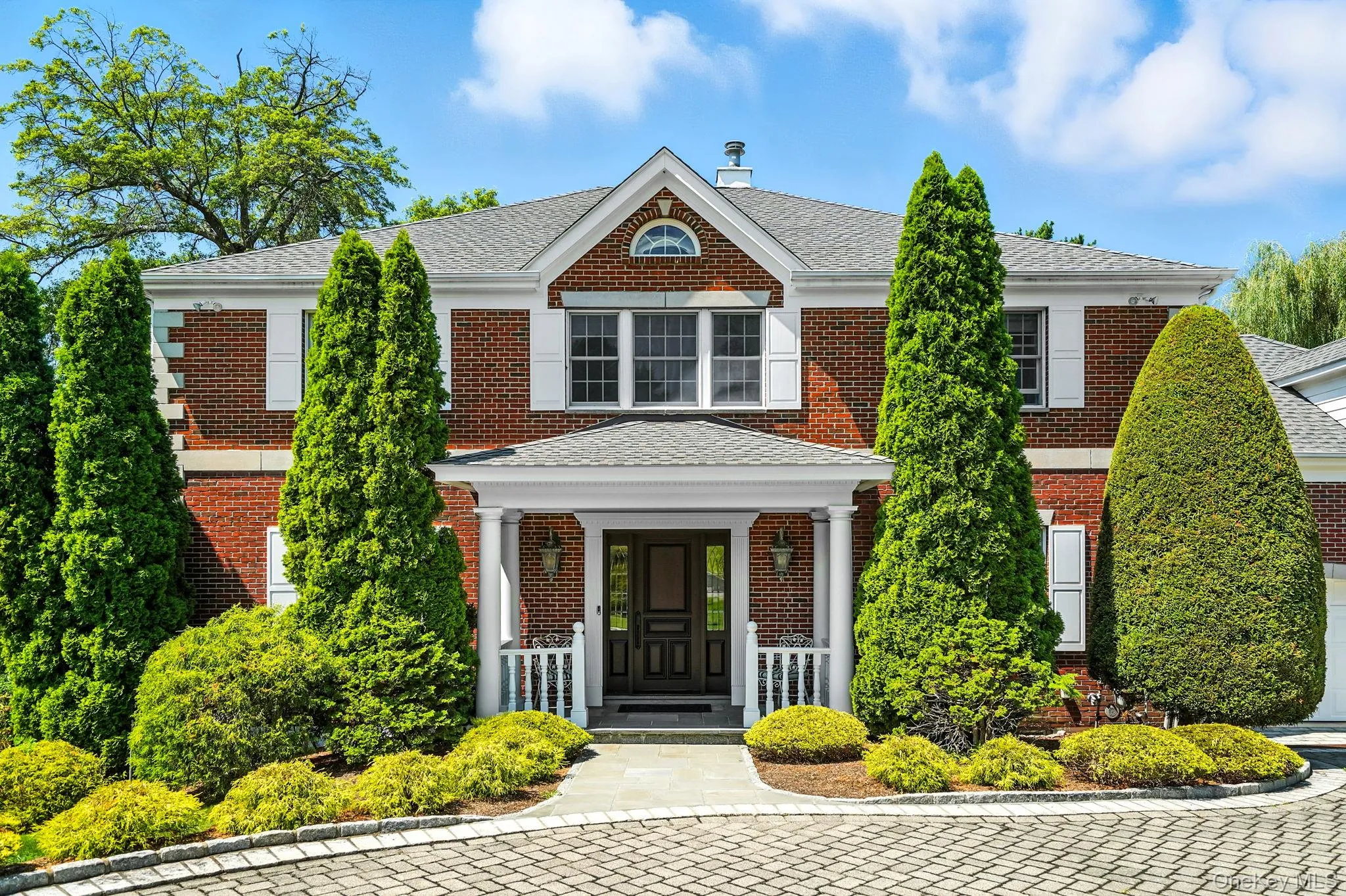 Colonial inspired home with brick siding, covered porch, and a shingled roof Colonial inspired home with brick siding, covered porch, and a shingled roof