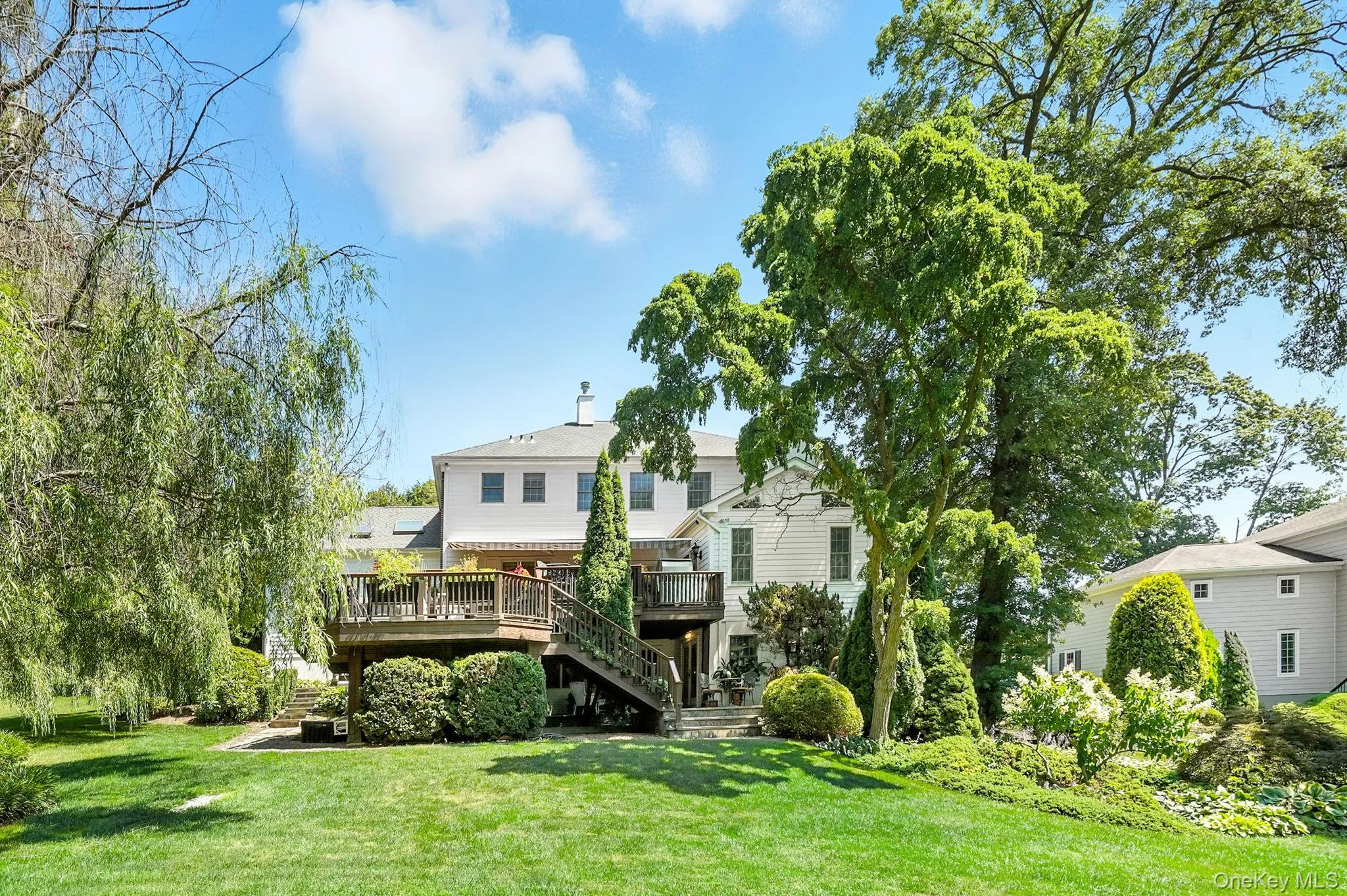 Rear view of property with stairs, a wooden deck, and a lawn Rear view of property with stairs, a wooden deck, and a lawn