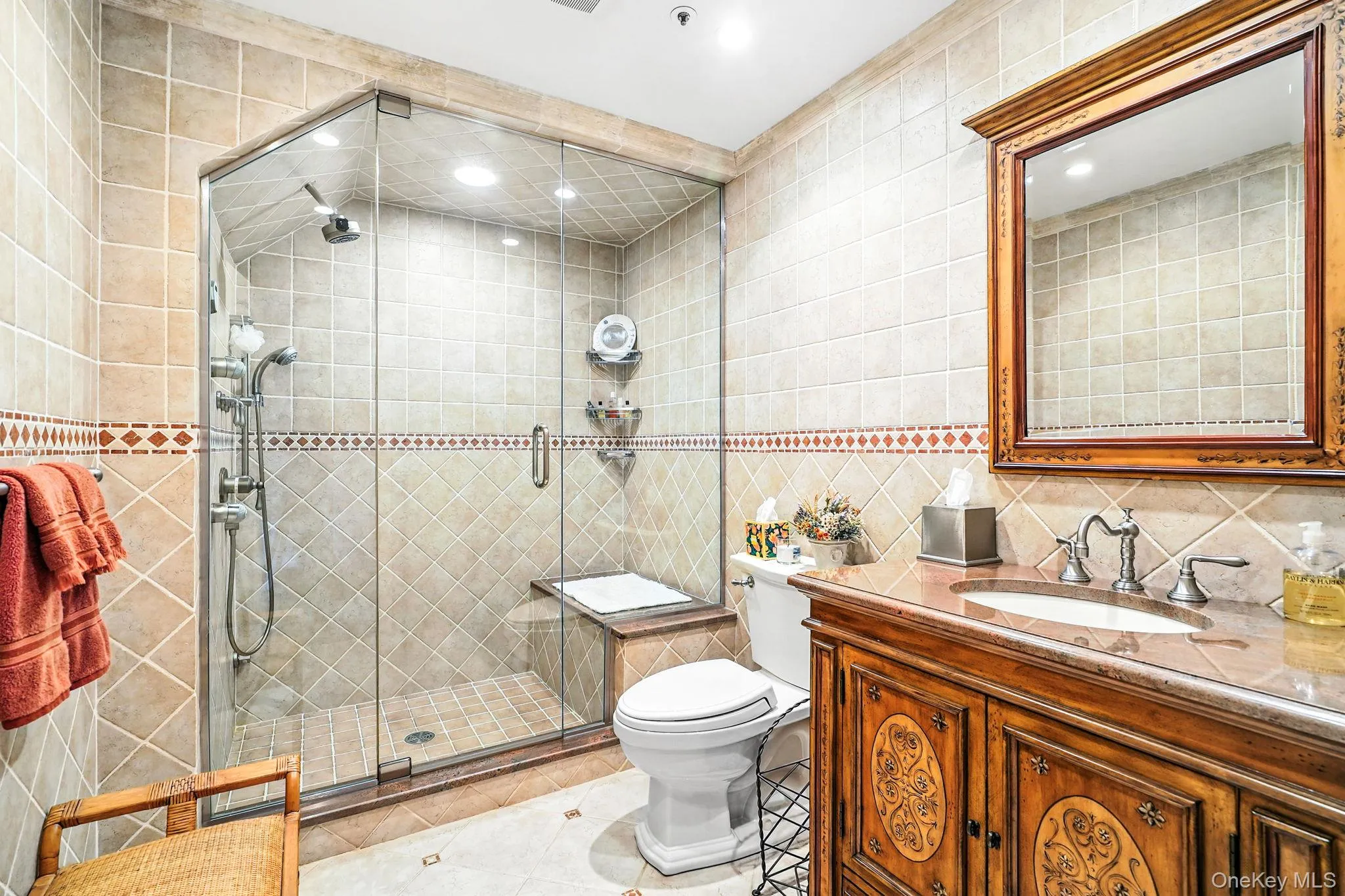 Bathroom in terrace level, featuring tile walls, a shower stall, vanity, light tile patterned floors, and backsplash Bathroom in terrace level, featuring tile walls, a shower stall, vanity, light tile patterned floors, and backsplash
