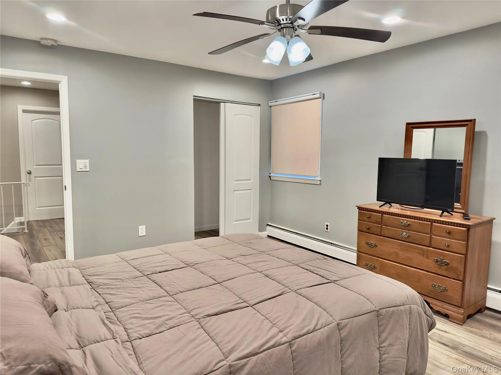 Bedroom with light wood finished floors, recessed lighting, baseboard heating, ceiling fan, and a closet Bedroom with light wood finished floors, recessed lighting, baseboard heating, ceiling fan, and a closet