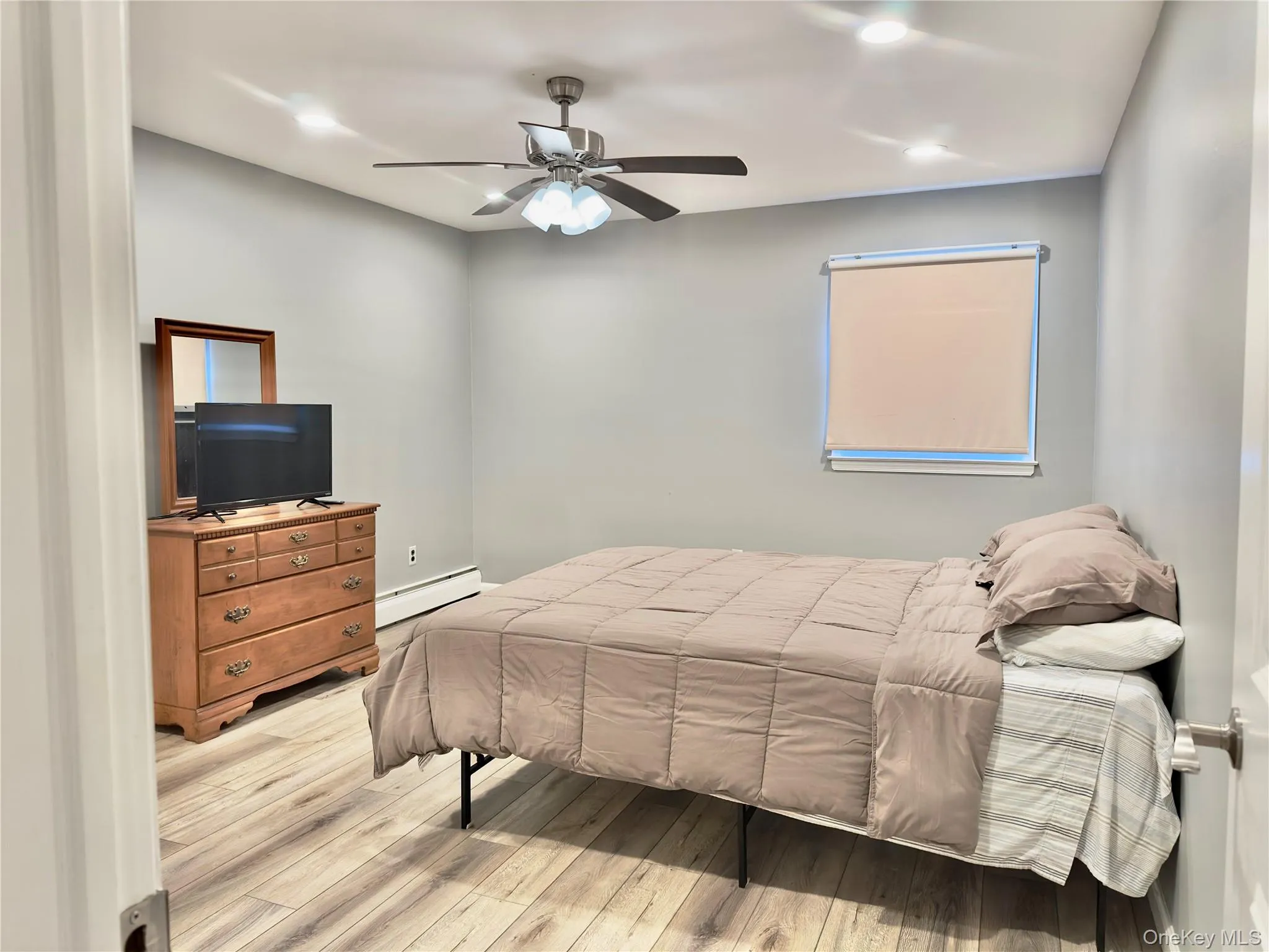 Bedroom featuring a baseboard heating unit, light wood-type flooring, a ceiling fan, and recessed lighting Bedroom featuring a baseboard heating unit, light wood-type flooring, a ceiling fan, and recessed lighting