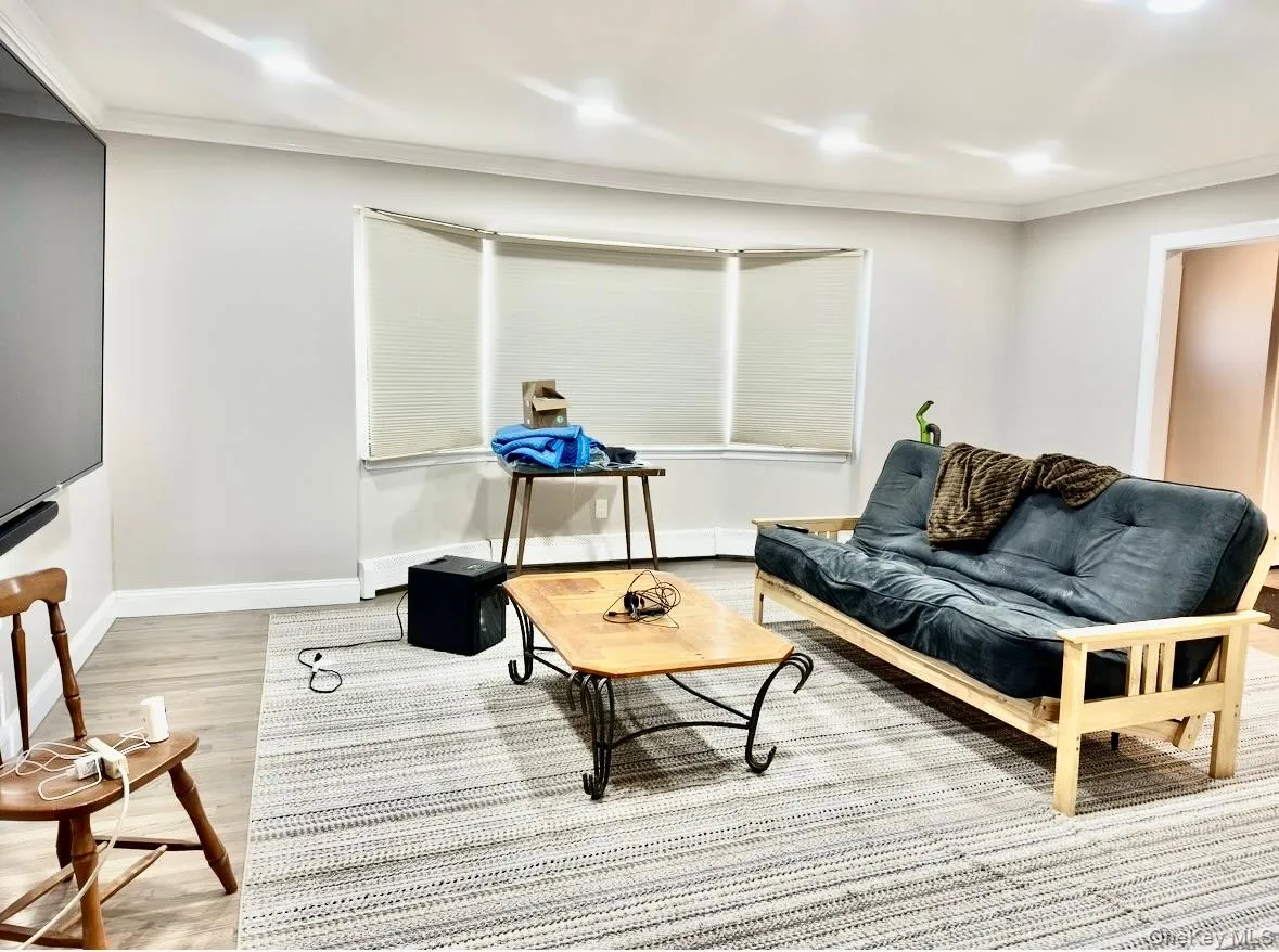 Living room featuring wood finished floors and crown molding Living room featuring wood finished floors and crown molding