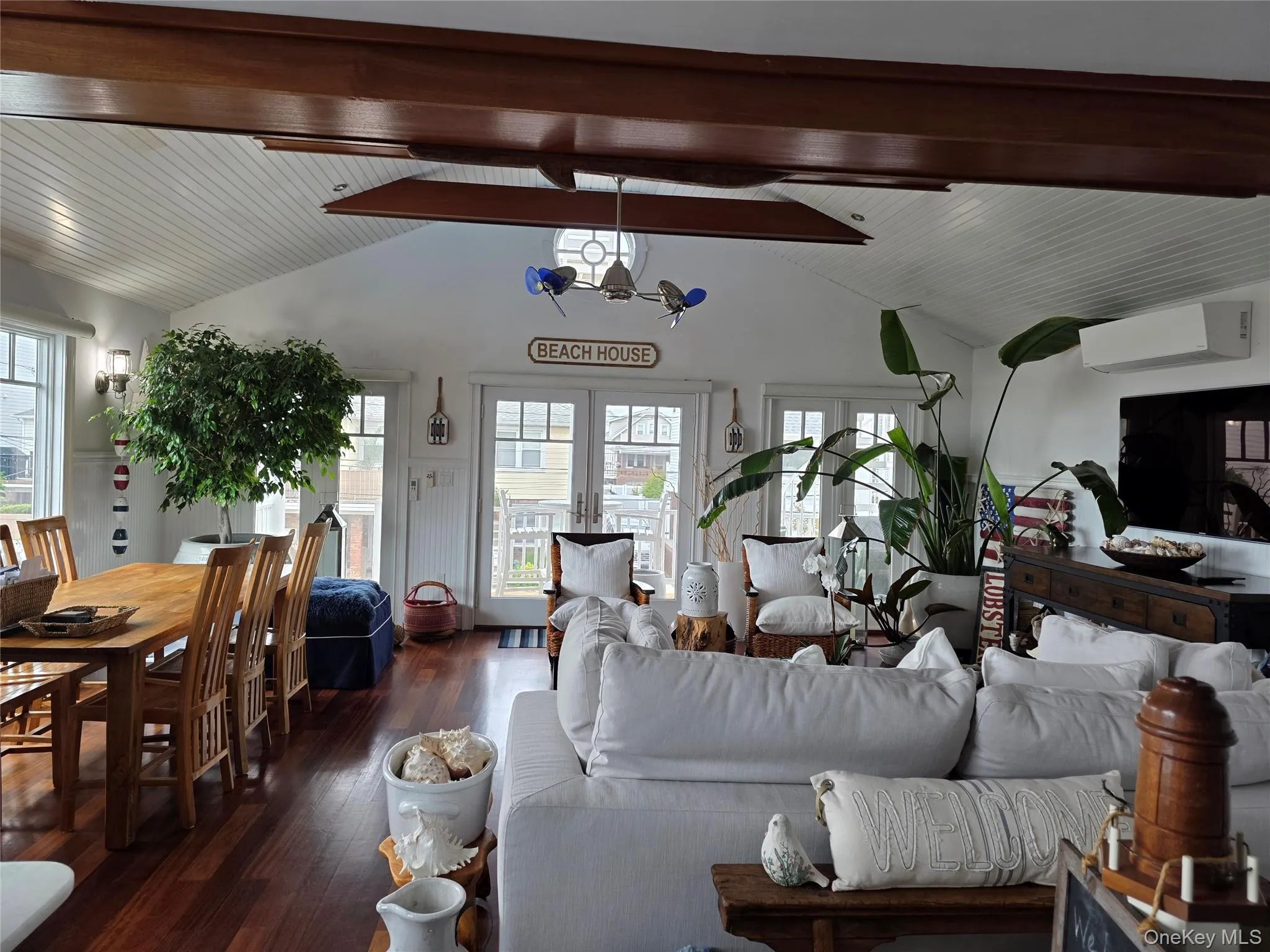 Living area with a wall mounted air conditioner, dark wood finished floors, and french doors Living area with a wall mounted air conditioner, dark wood finished floors, and french doors
