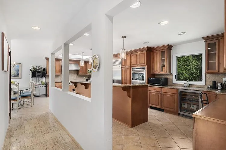 Kitchen featuring stainless steel appliances, decorative backsplash, beverage cooler, extractor fan, and recessed lighting Kitchen featuring stainless steel appliances, decorative backsplash, beverage cooler, extractor fan, and recessed lighting