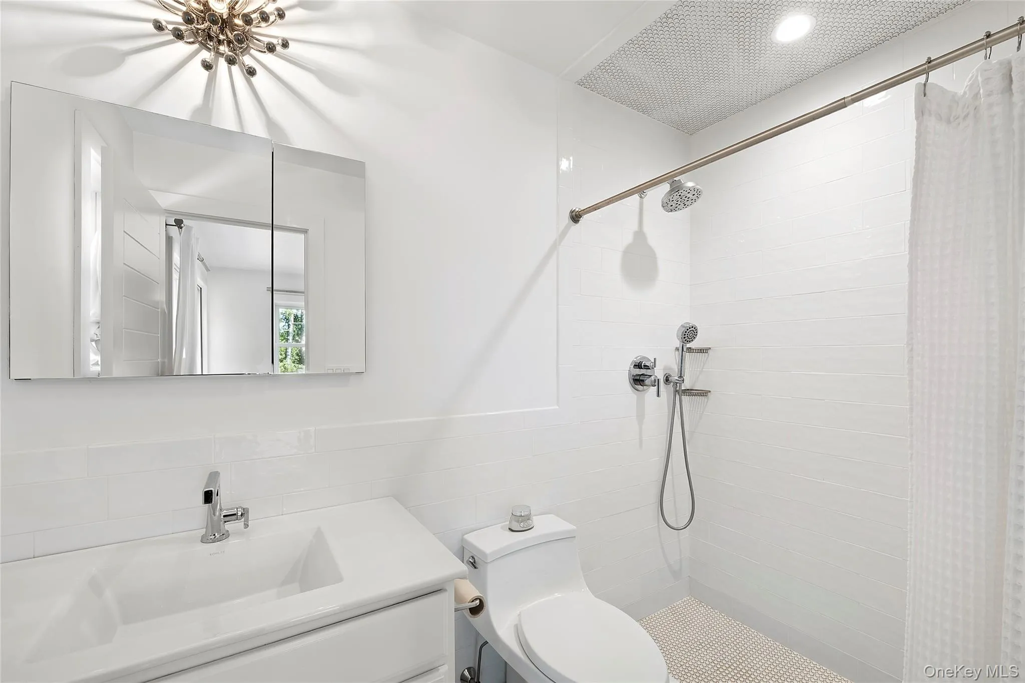 Full bath featuring a tile shower, vanity, tile walls, and wainscoting Full bath featuring a tile shower, vanity, tile walls, and wainscoting