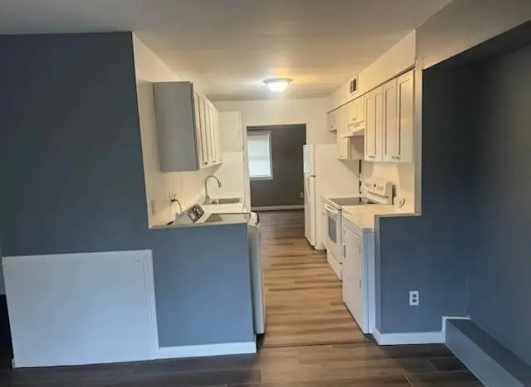 Kitchen with white range with electric cooktop, wood finished floors, light countertops, and white cabinets Kitchen with white range with electric cooktop, wood finished floors, light countertops, and white cabinets