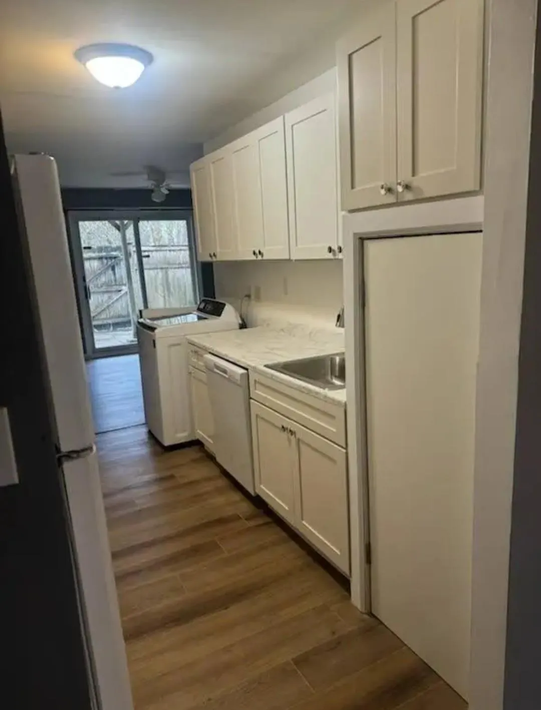 Kitchen featuring dark wood finished floors, freestanding refrigerator, white cabinets, and washer / clothes dryer Kitchen featuring dark wood finished floors, freestanding refrigerator, white cabinets, and washer / clothes dryer
