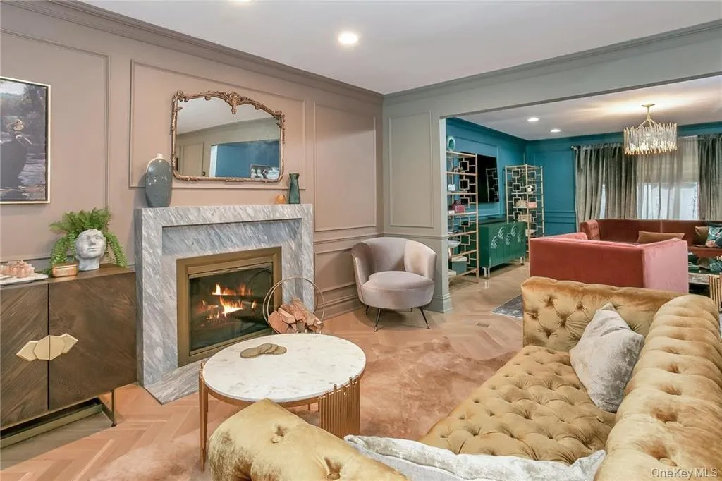 Living room featuring a decorative wall, a chandelier, recessed lighting, a high end fireplace, and ornamental molding Living room featuring a decorative wall, a chandelier, recessed lighting, a high end fireplace, and ornamental molding