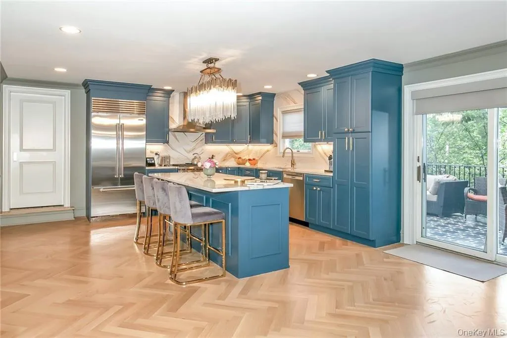Kitchen with blue cabinetry, light countertops, stainless steel appliances, a breakfast bar, and extractor fan Kitchen with blue cabinetry, light countertops, stainless steel appliances, a breakfast bar, and extractor fan