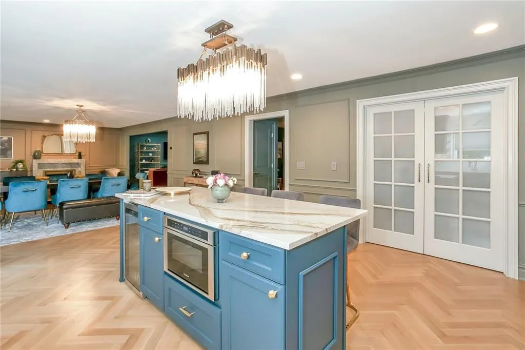 Kitchen with a chandelier, a decorative wall, blue cabinets, recessed lighting, and a kitchen island Kitchen with a chandelier, a decorative wall, blue cabinets, recessed lighting, and a kitchen island
