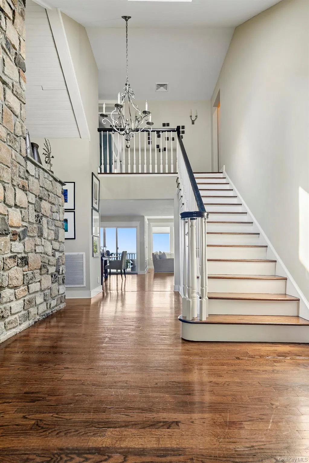 Staircase featuring wood finished floors, a chandelier, and a towering ceiling Staircase featuring wood finished floors, a chandelier, and a towering ceiling