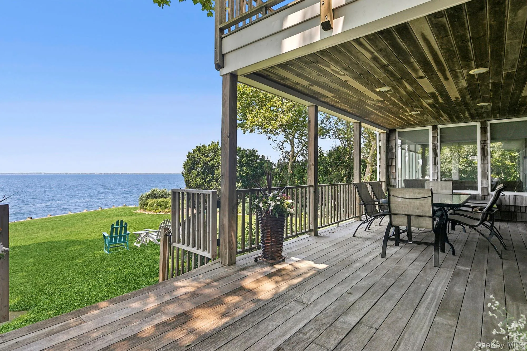 Deck featuring a water view, a lawn, and outdoor dining area Deck featuring a water view, a lawn, and outdoor dining area