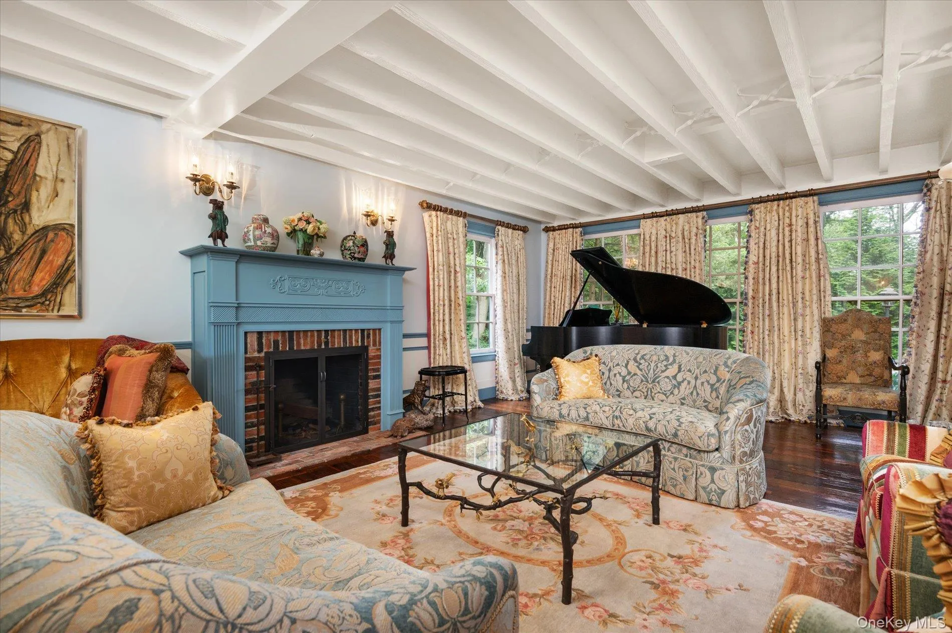 Living room with beamed ceiling, wood finished floors, and a brick fireplace Living room with beamed ceiling, wood finished floors, and a brick fireplace