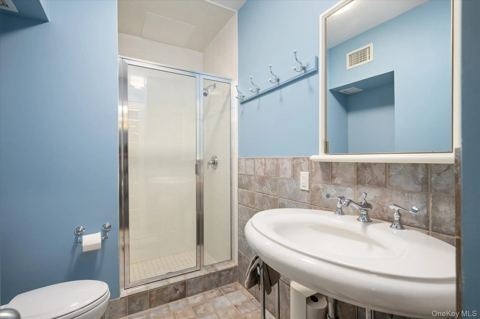 Bathroom featuring a shower stall and tile walls Bathroom featuring a shower stall and tile walls