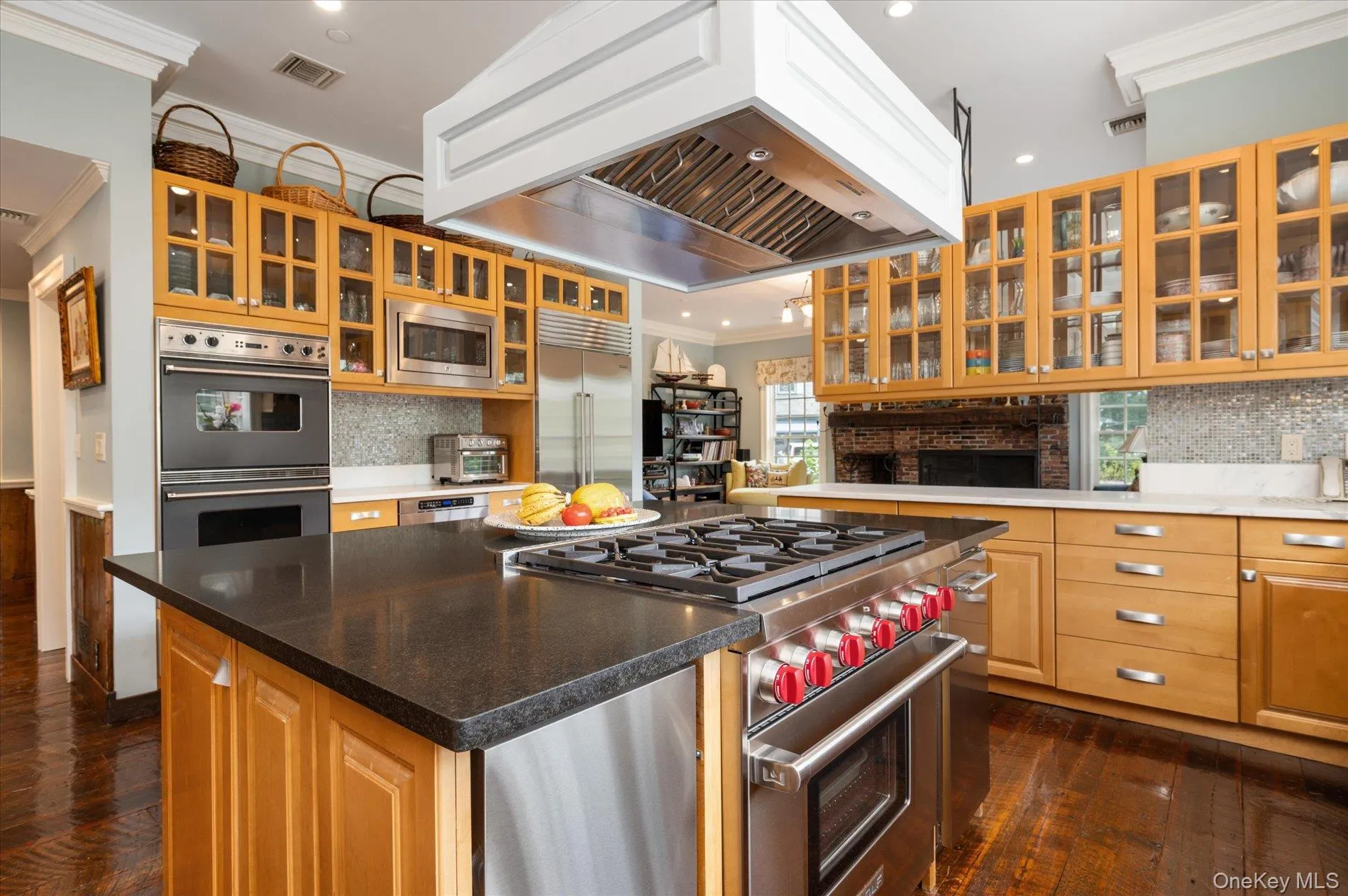 Kitchen featuring crown molding, tasteful backsplash, custom exhaust hood, built in appliances, and dark wood-type flooring Kitchen featuring crown molding, tasteful backsplash, custom exhaust hood, built in appliances, and dark wood-type flooring