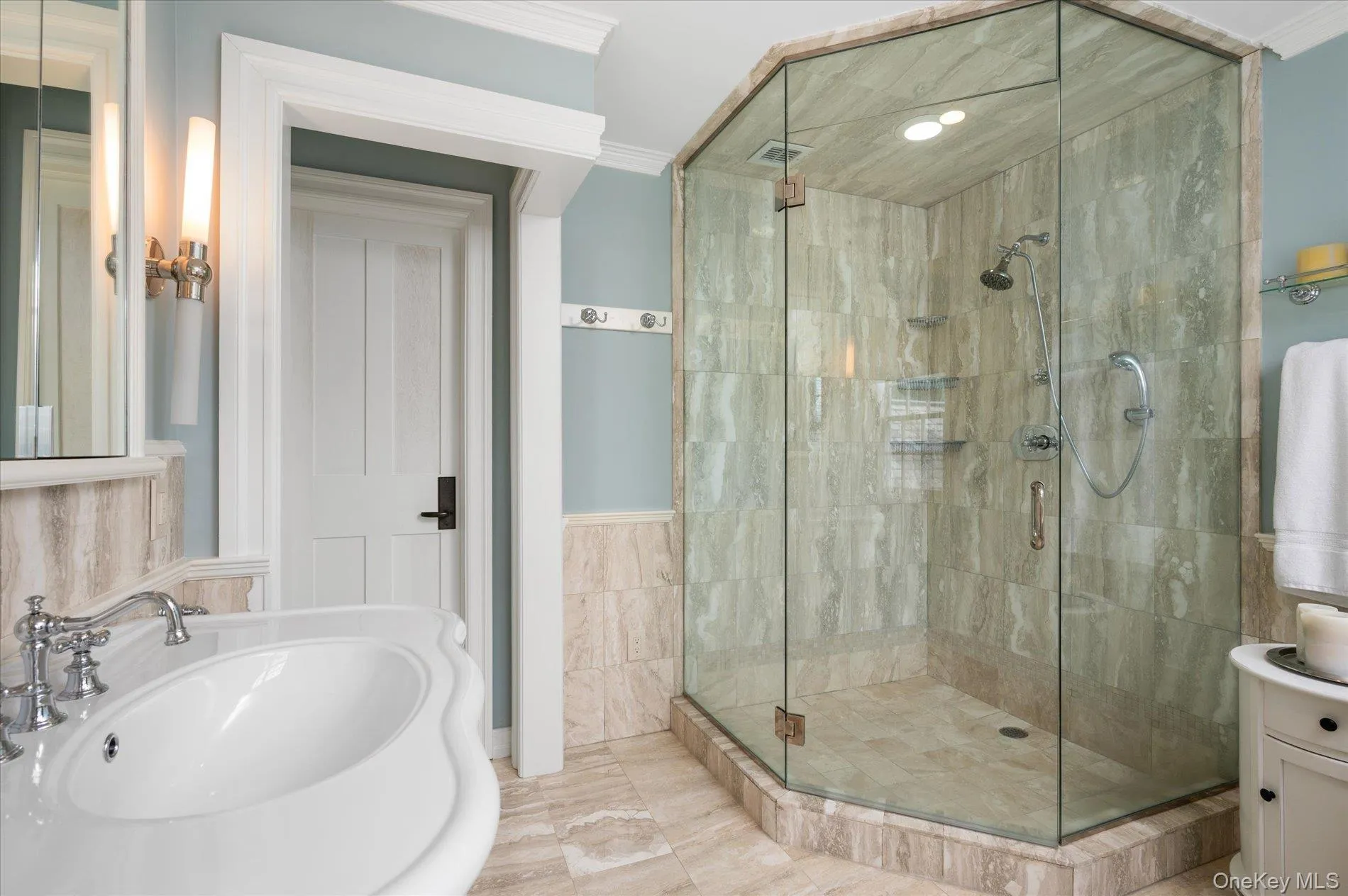 Bathroom featuring ornamental molding, a stall shower, tile walls, and wainscoting Bathroom featuring ornamental molding, a stall shower, tile walls, and wainscoting