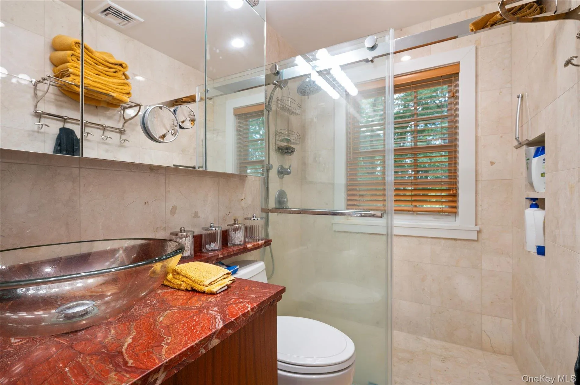 Bathroom featuring plenty of natural light, a stall shower, tile walls, and vanity Bathroom featuring plenty of natural light, a stall shower, tile walls, and vanity