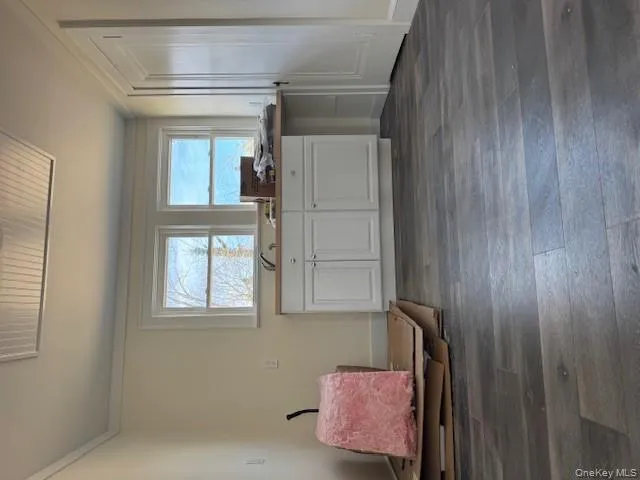 Kitchen featuring ornamental molding, dark wood-style flooring, and white cabinetry Kitchen featuring ornamental molding, dark wood-style flooring, and white cabinetry