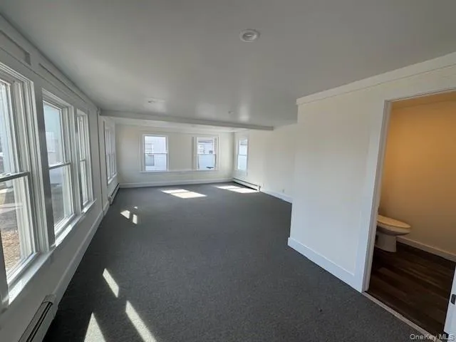 Unfurnished room featuring dark carpet, a baseboard radiator, and ornamental molding Unfurnished room featuring dark carpet, a baseboard radiator, and ornamental molding