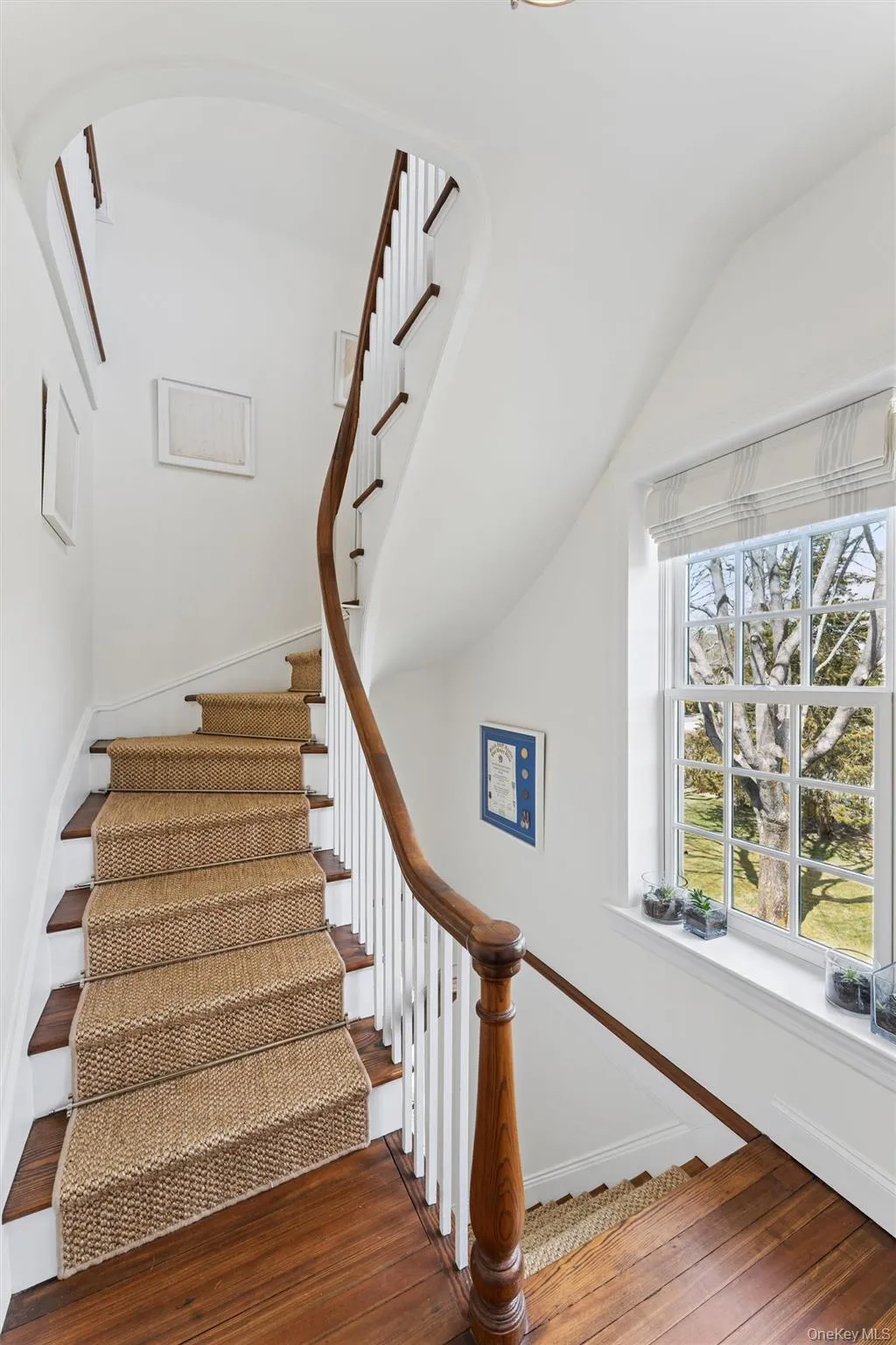 Stairway with arched walkways, vaulted ceiling, baseboards, and hardwood / wood-style floors Stairway with arched walkways, vaulted ceiling, baseboards, and hardwood / wood-style floors