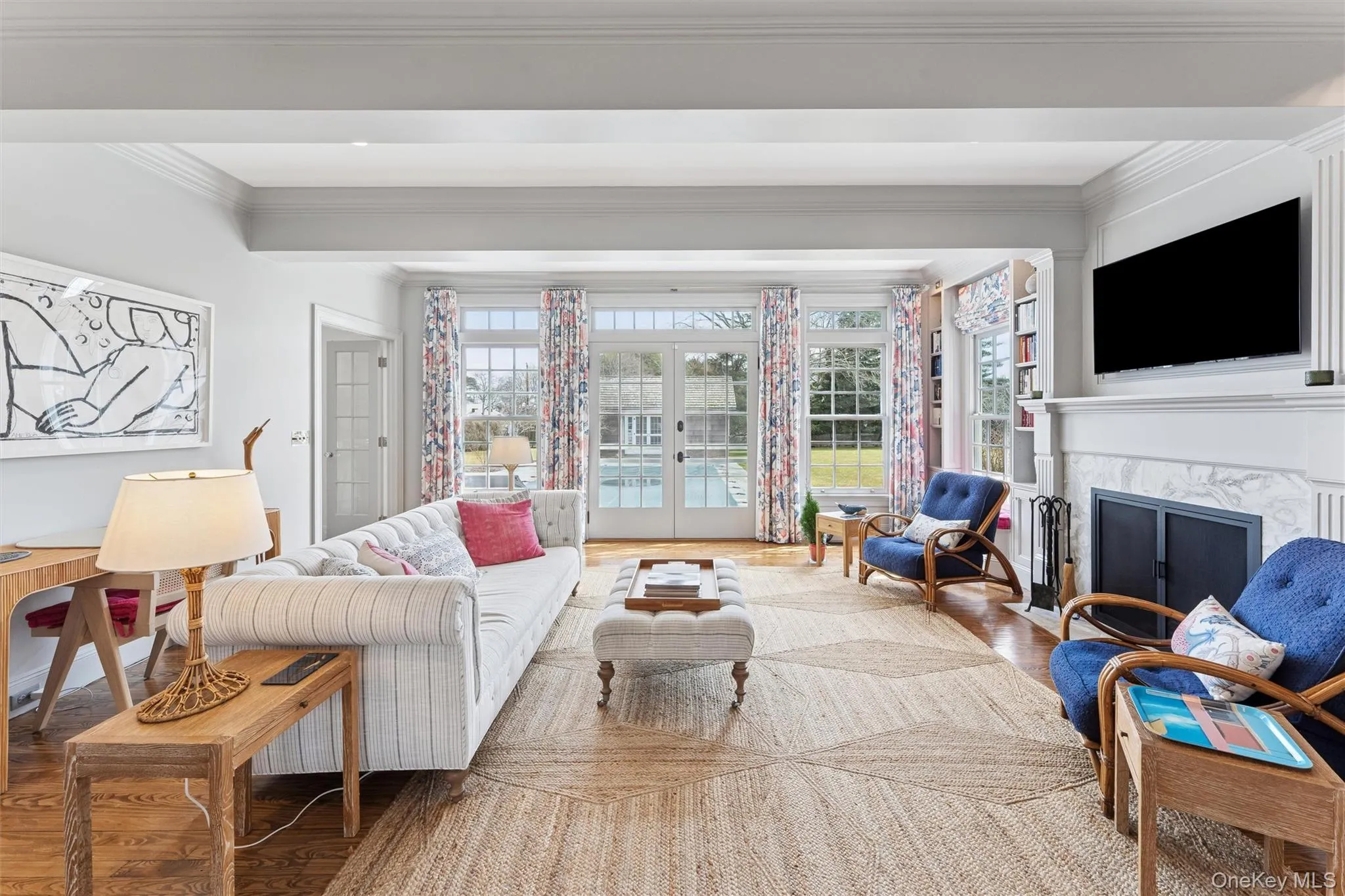 Living room featuring wood finished floors, a premium fireplace, beam ceiling, french doors, and crown molding Living room featuring wood finished floors, a premium fireplace, beam ceiling, french doors, and crown molding