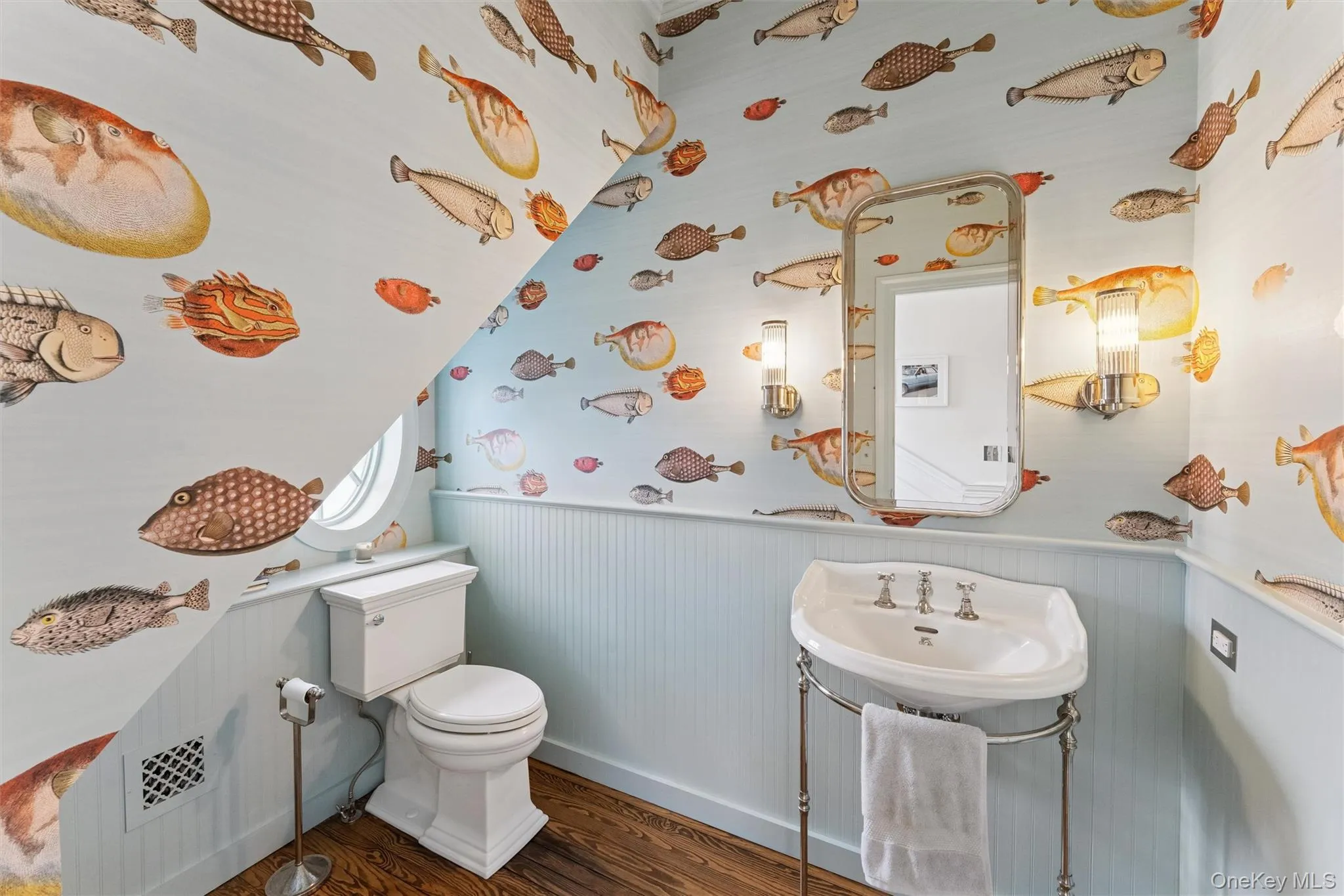 Half bathroom with a sink, a wainscoted wall, toilet, and wood finished floors Half bathroom with a sink, a wainscoted wall, toilet, and wood finished floors