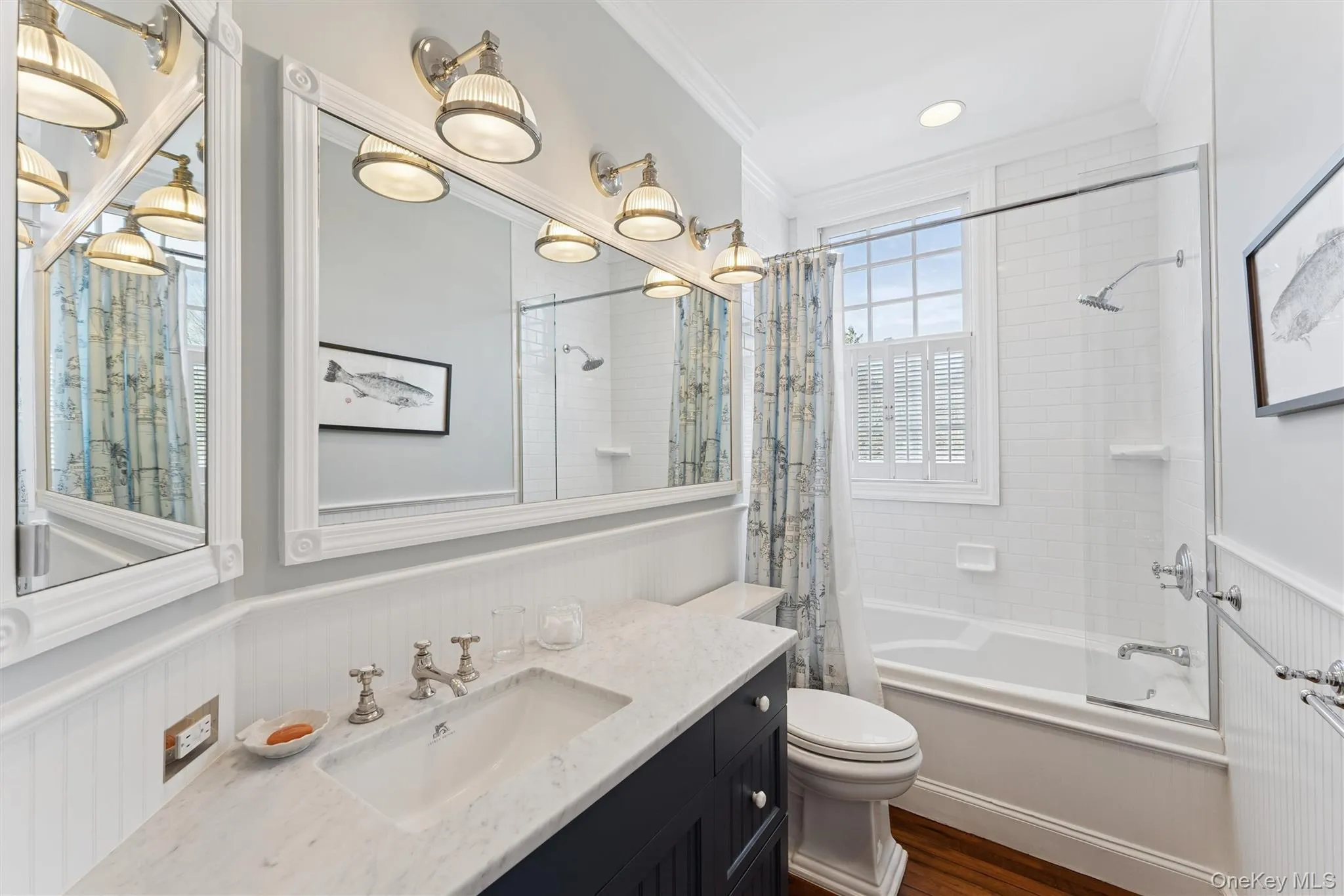 Full bath with vanity, a wainscoted wall, ornamental molding, shower / tub combo, and toilet Full bath with vanity, a wainscoted wall, ornamental molding, shower / tub combo, and toilet